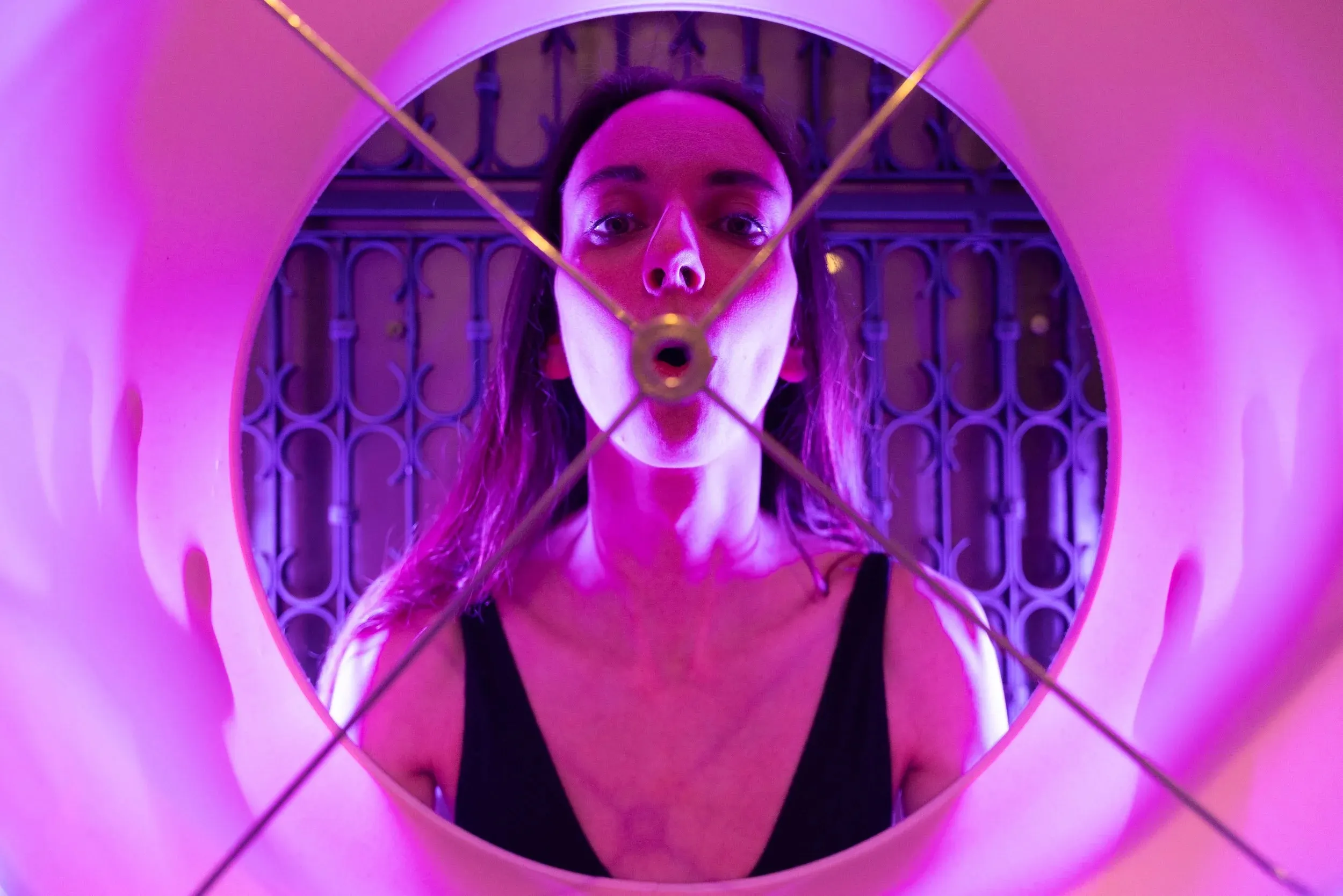 A face and open mouth fill the round frame of a lampshade.