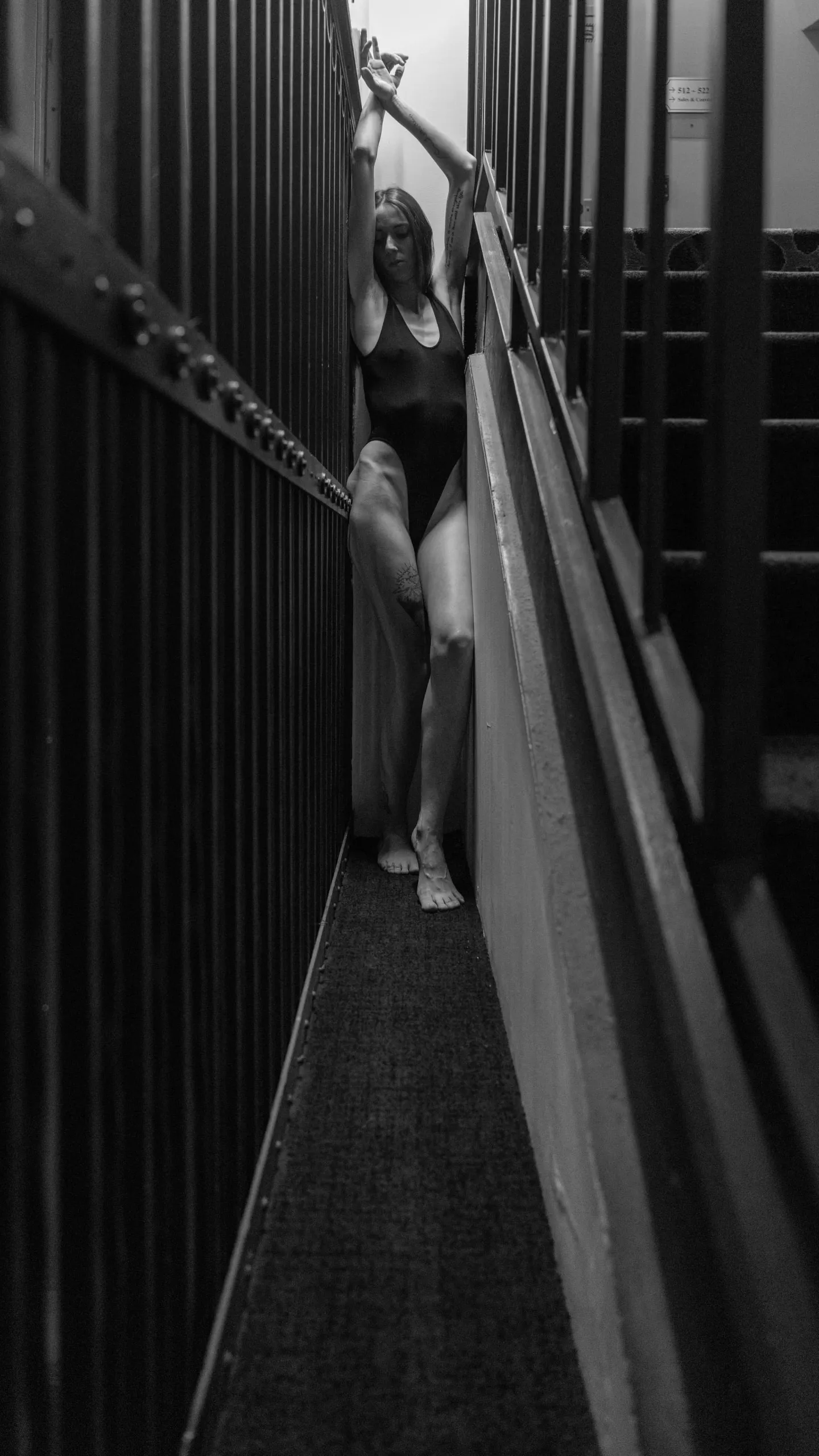 A woman is wedged between a metal staircase and a metal grate.