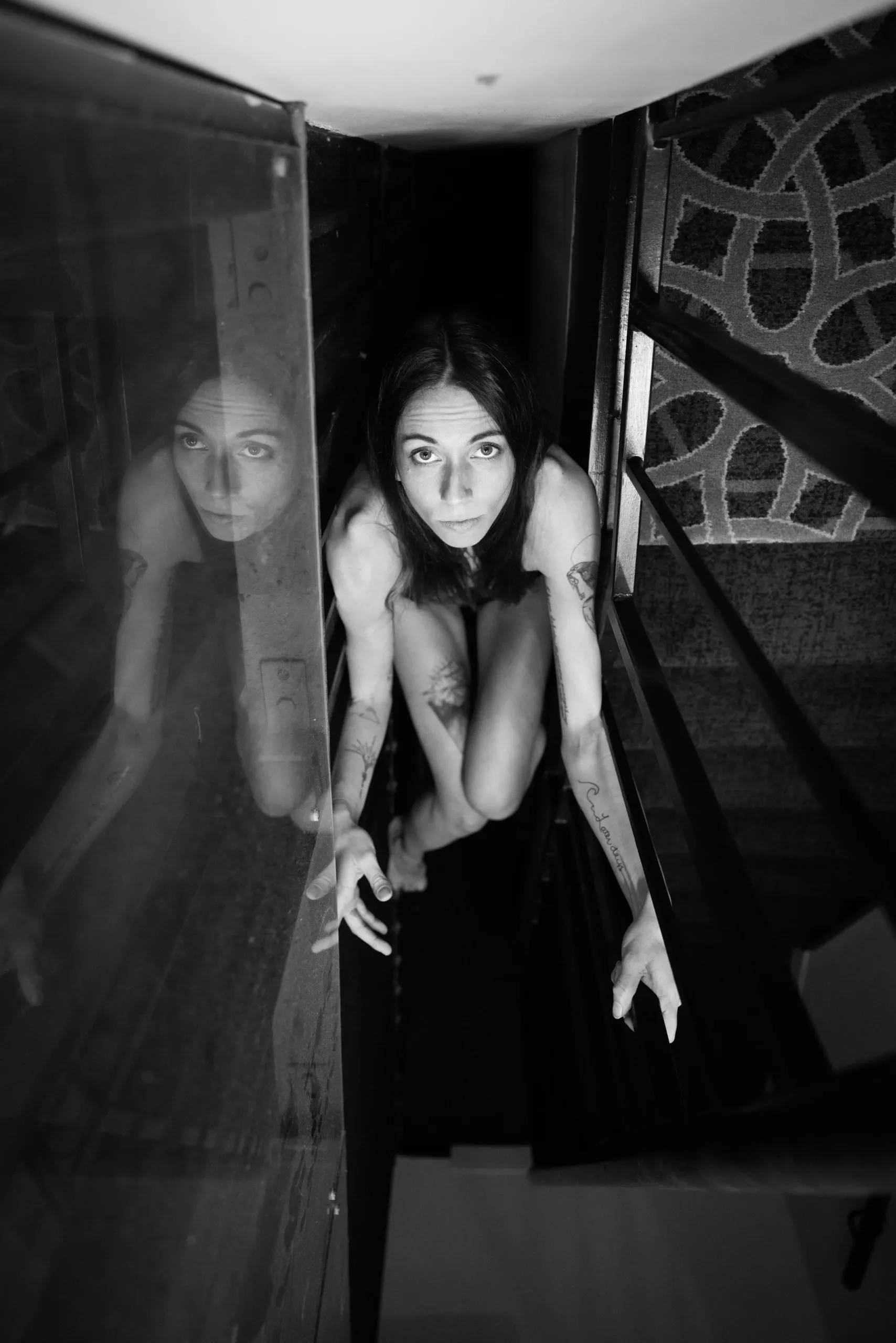A woman looks upward from a narrow opening in which she is wedged.