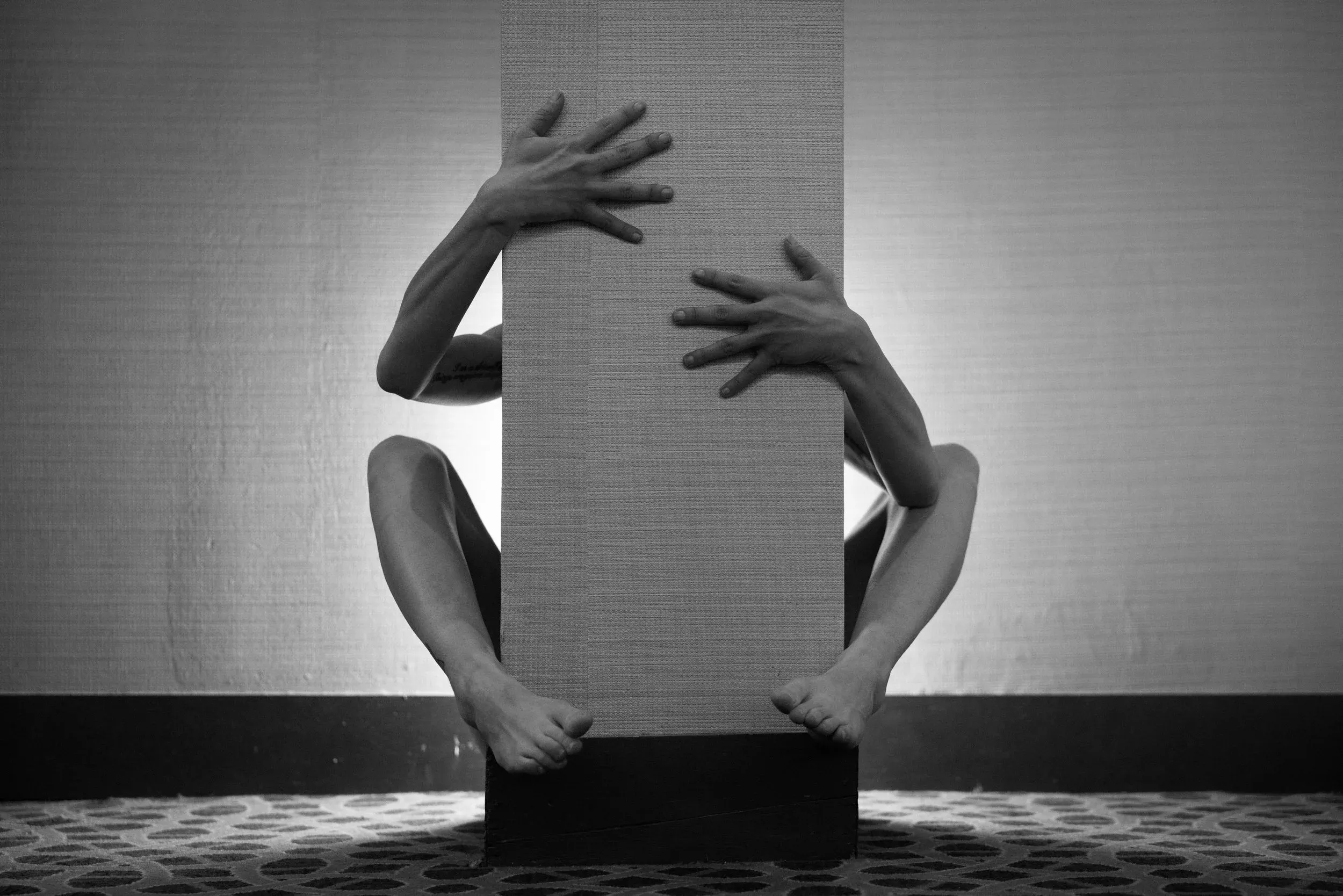 Hands and feet wrap around a support column; the woman's body is hidden.