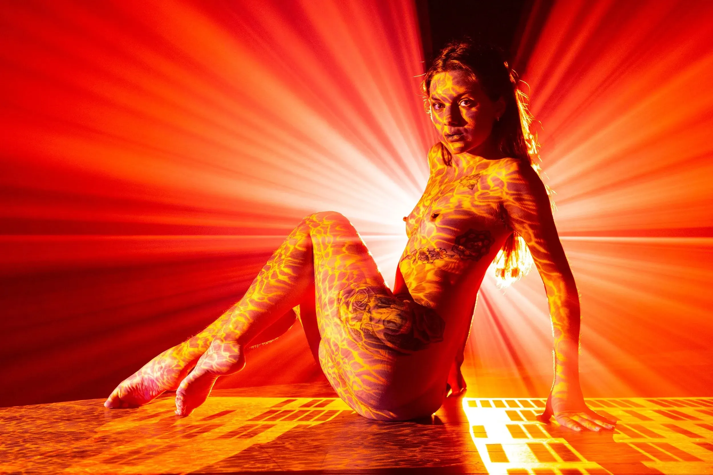 A seated woman is surrounded by intense red-orange rays.