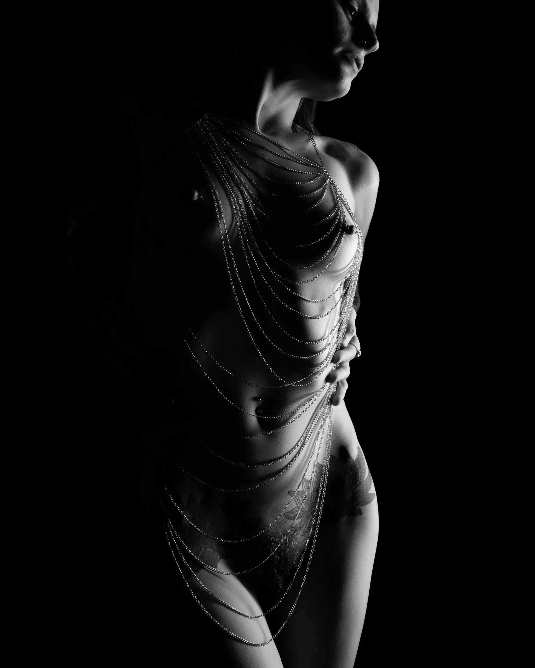 A standing figure wrapped in chains is outlined by narrow side light.