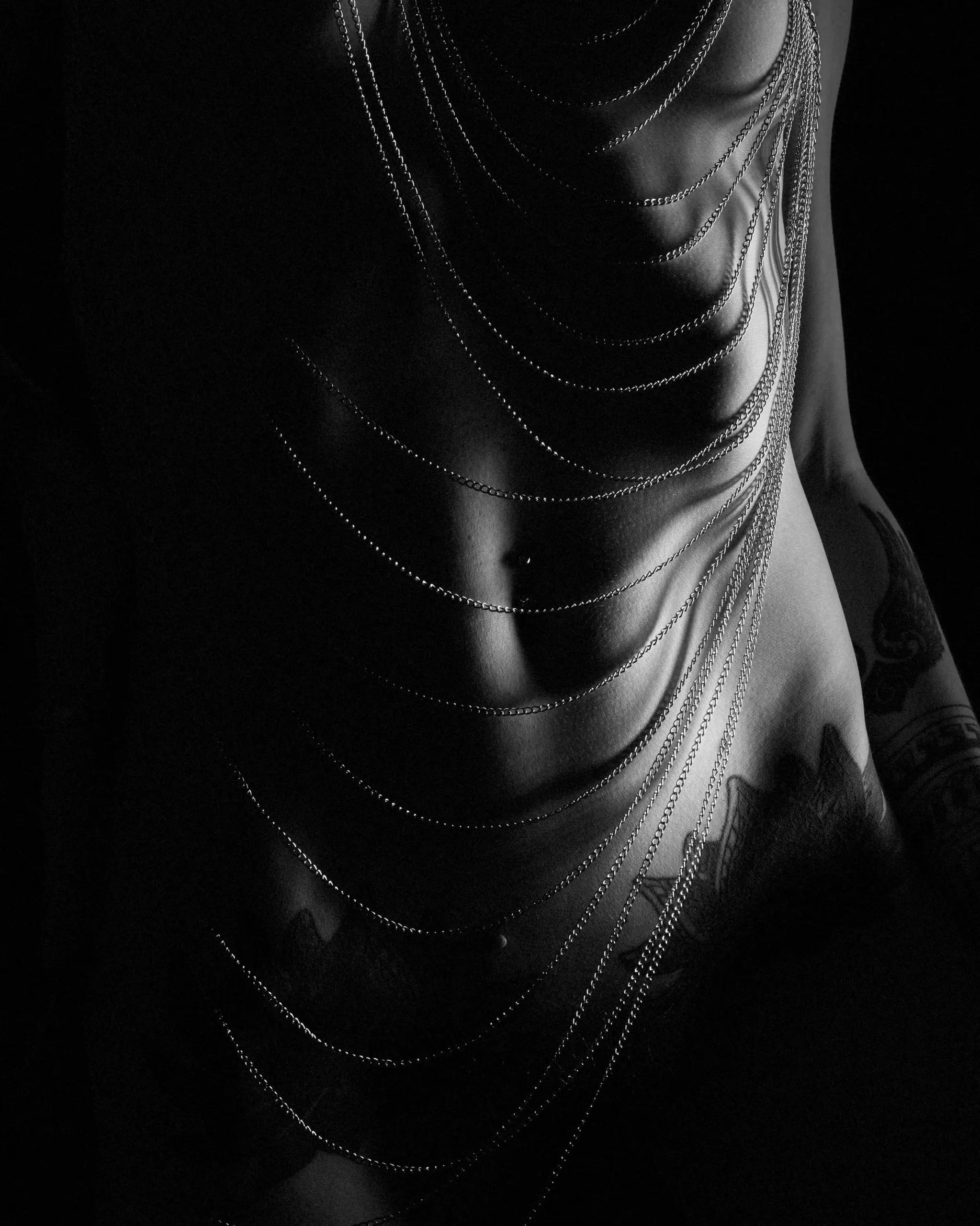 Layered chains sweep across a torso in a high-contrast black-and-white crop.