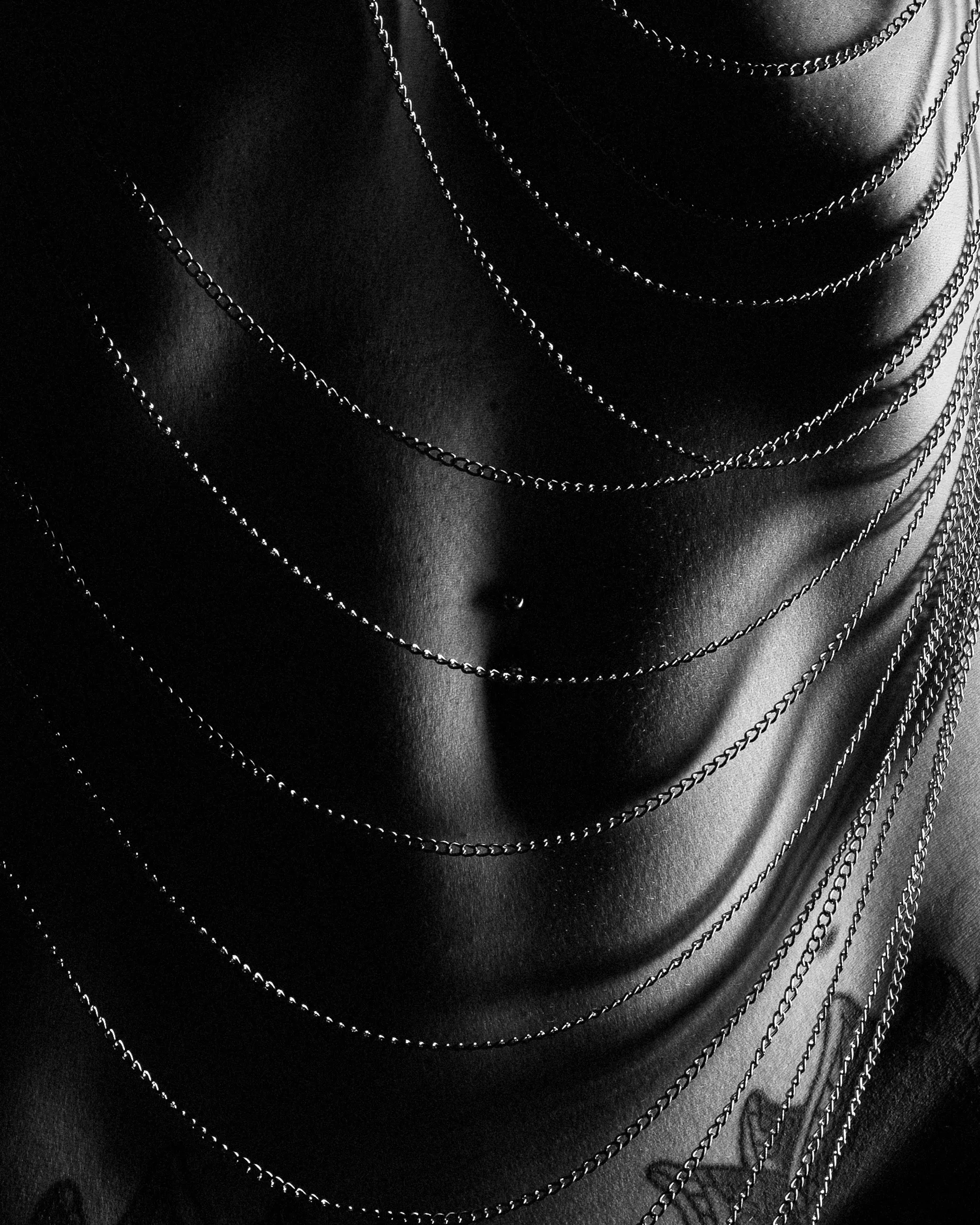 Fine chains form bright arcs across a close-cropped torso.