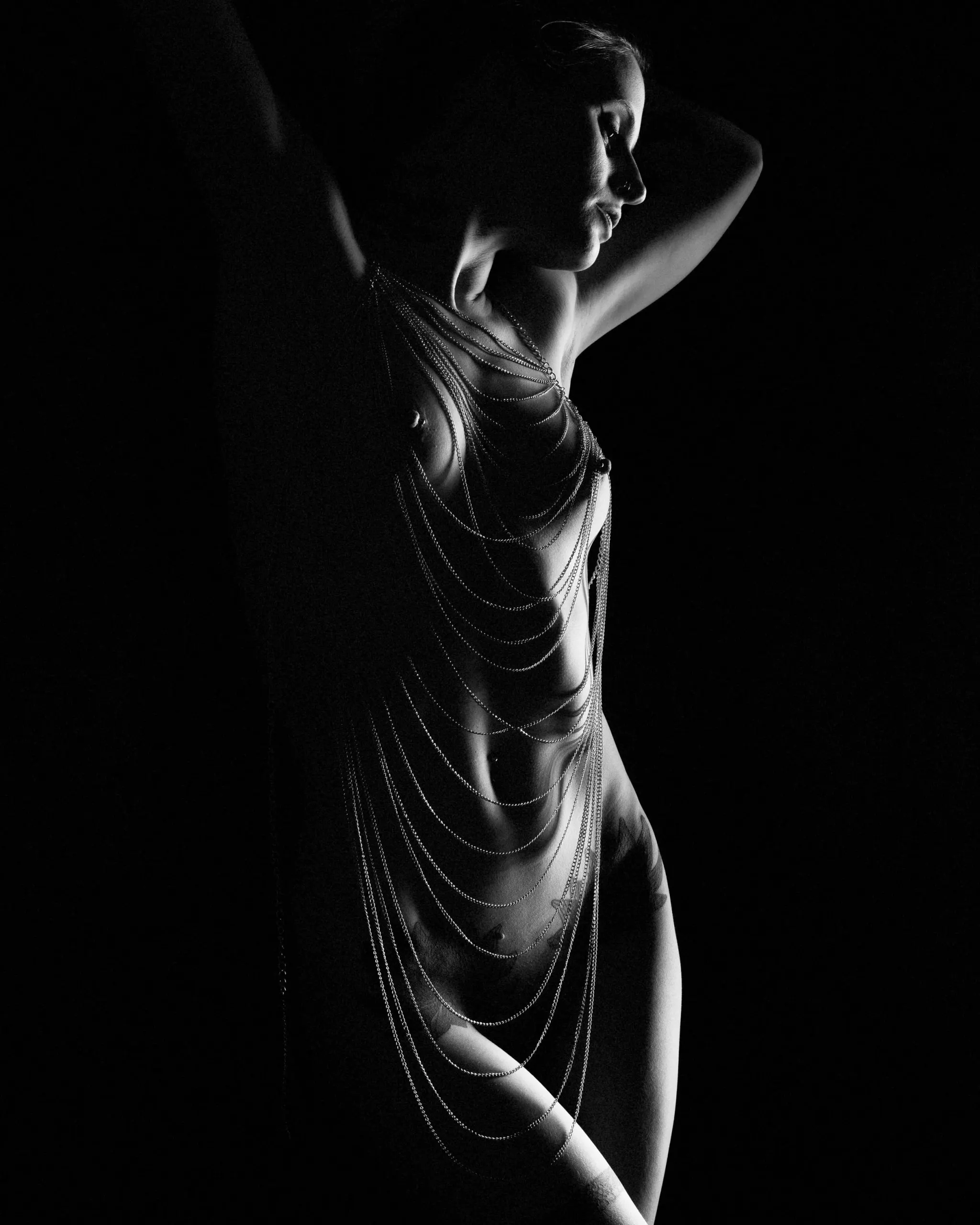 A standing figure wrapped in chains lifts one arm into the darkness.