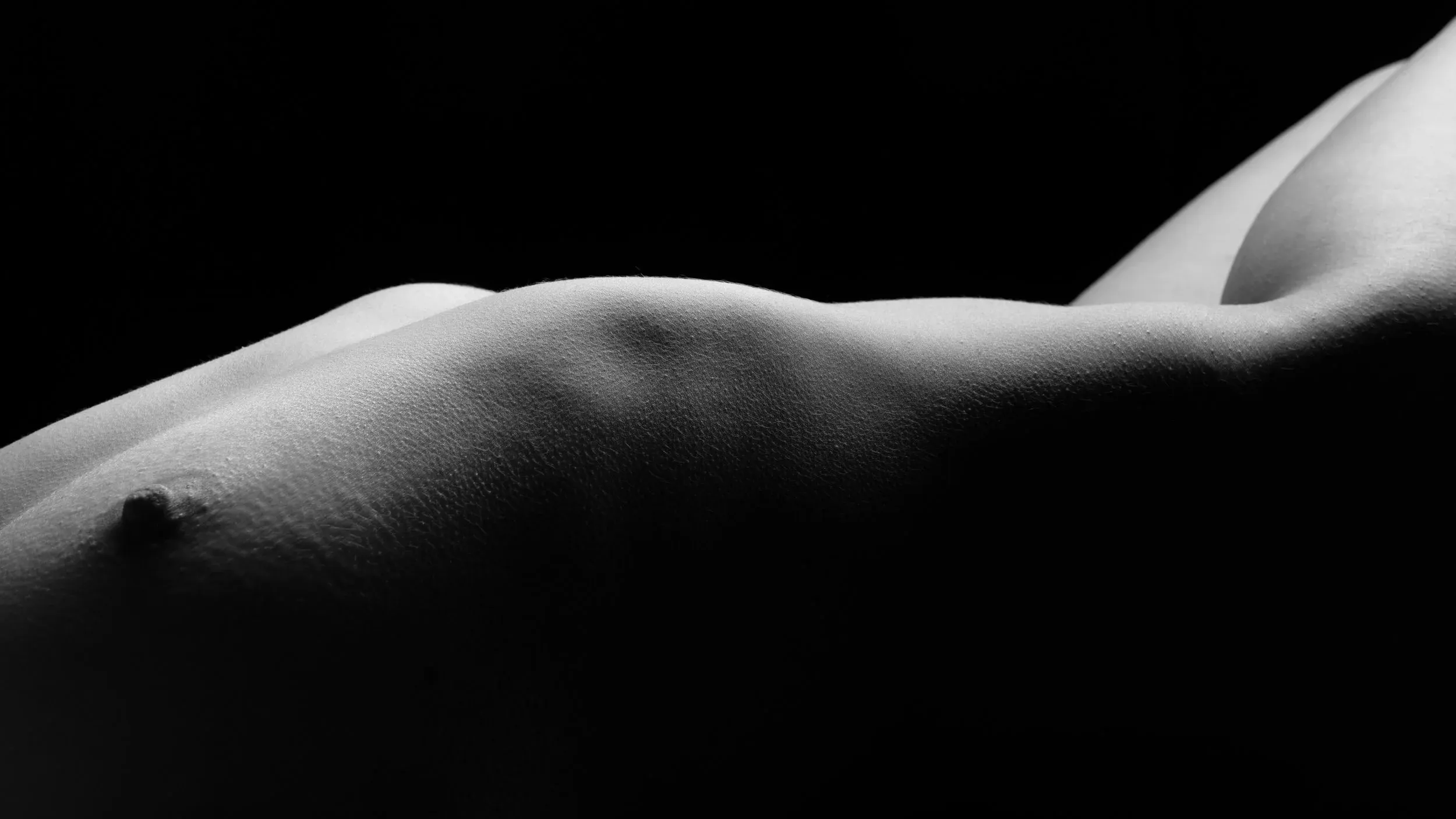 A reclining torso rises from darkness in a long horizontal curve.