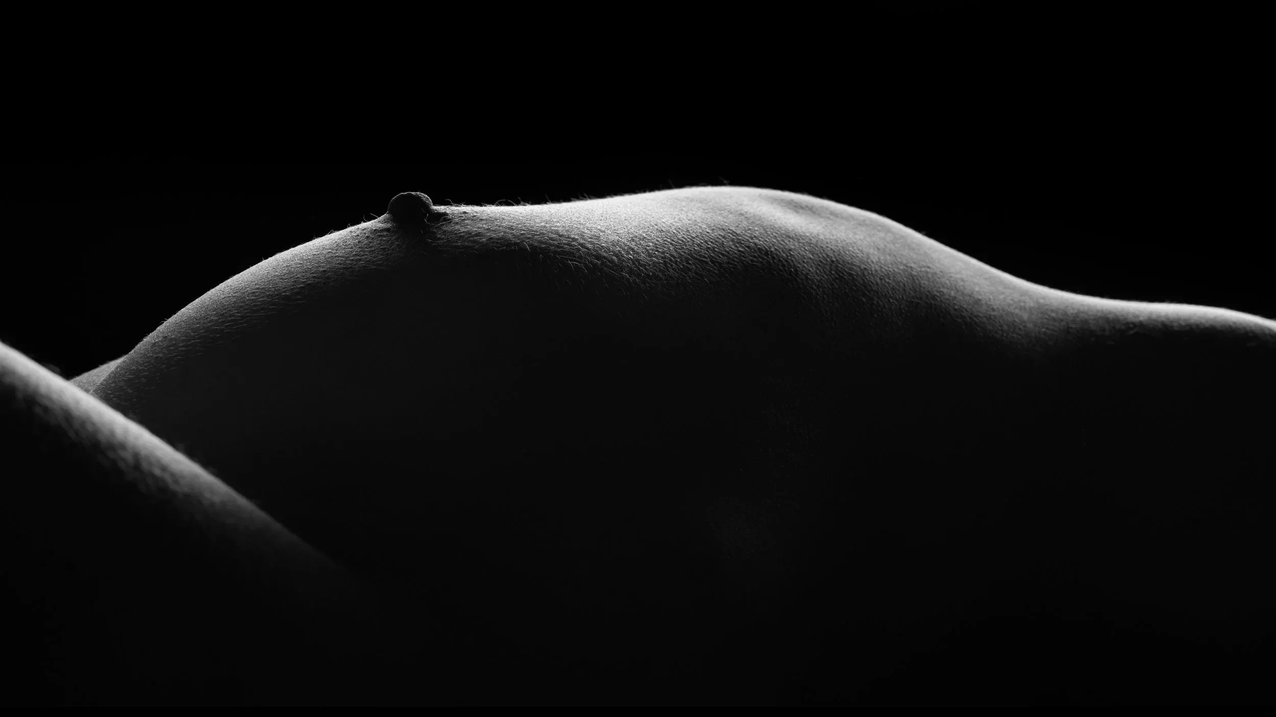 A low side view bodyscape reduces a reclining figure to one luminous ridge.