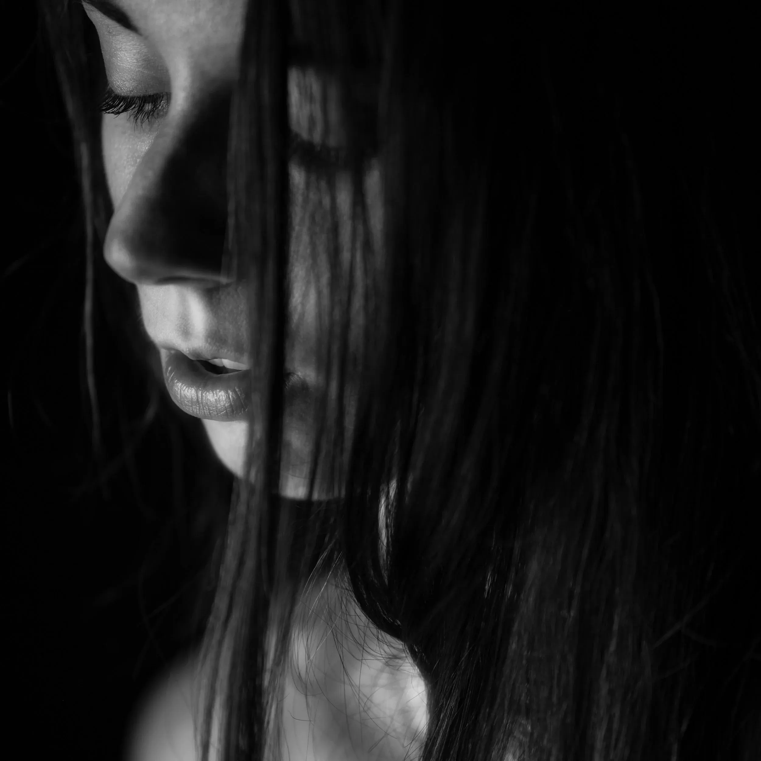 A close black-and-white portrait peers through strands of dark hair.