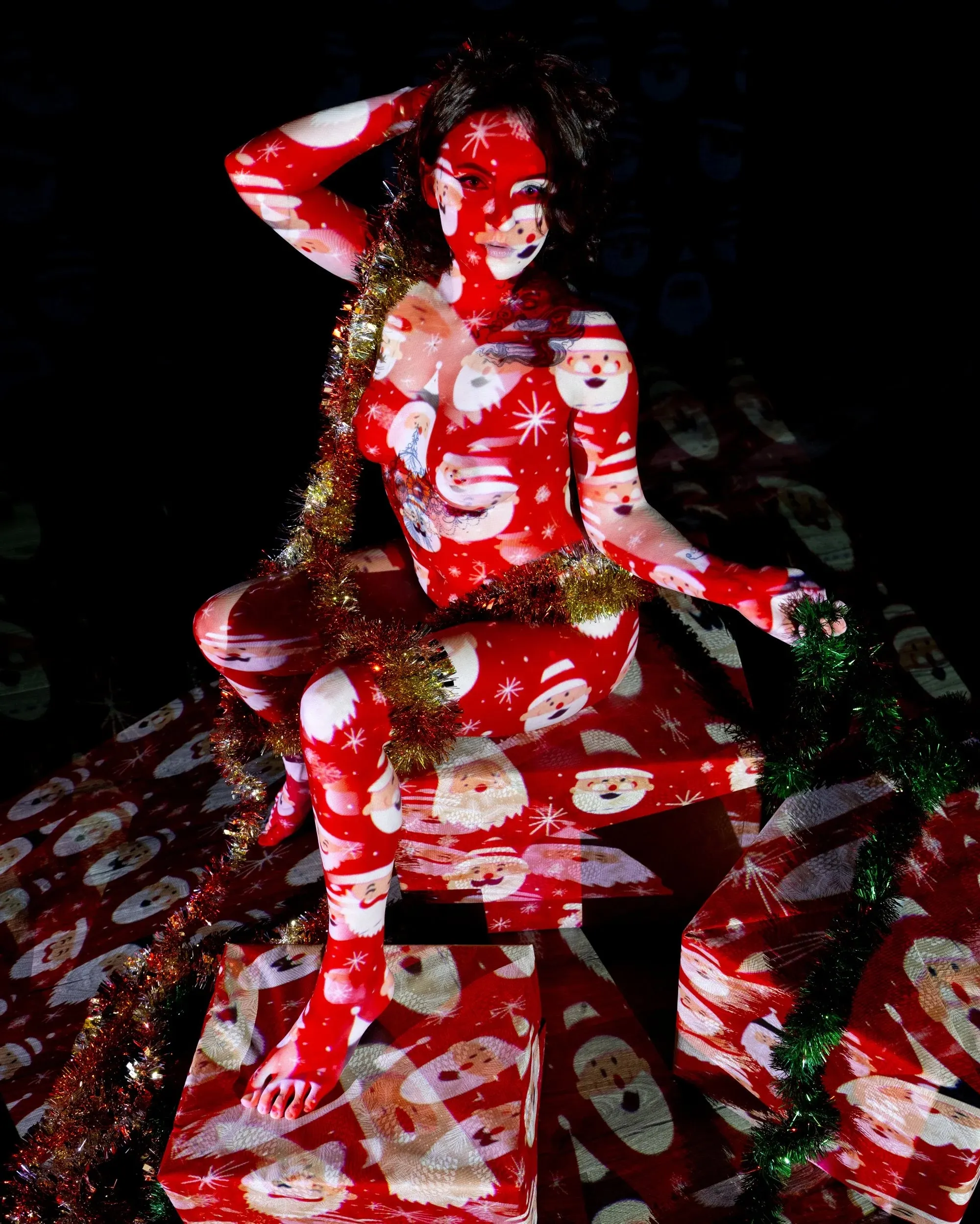 Red holiday patterns cover a seated woman and stacked gift boxes.