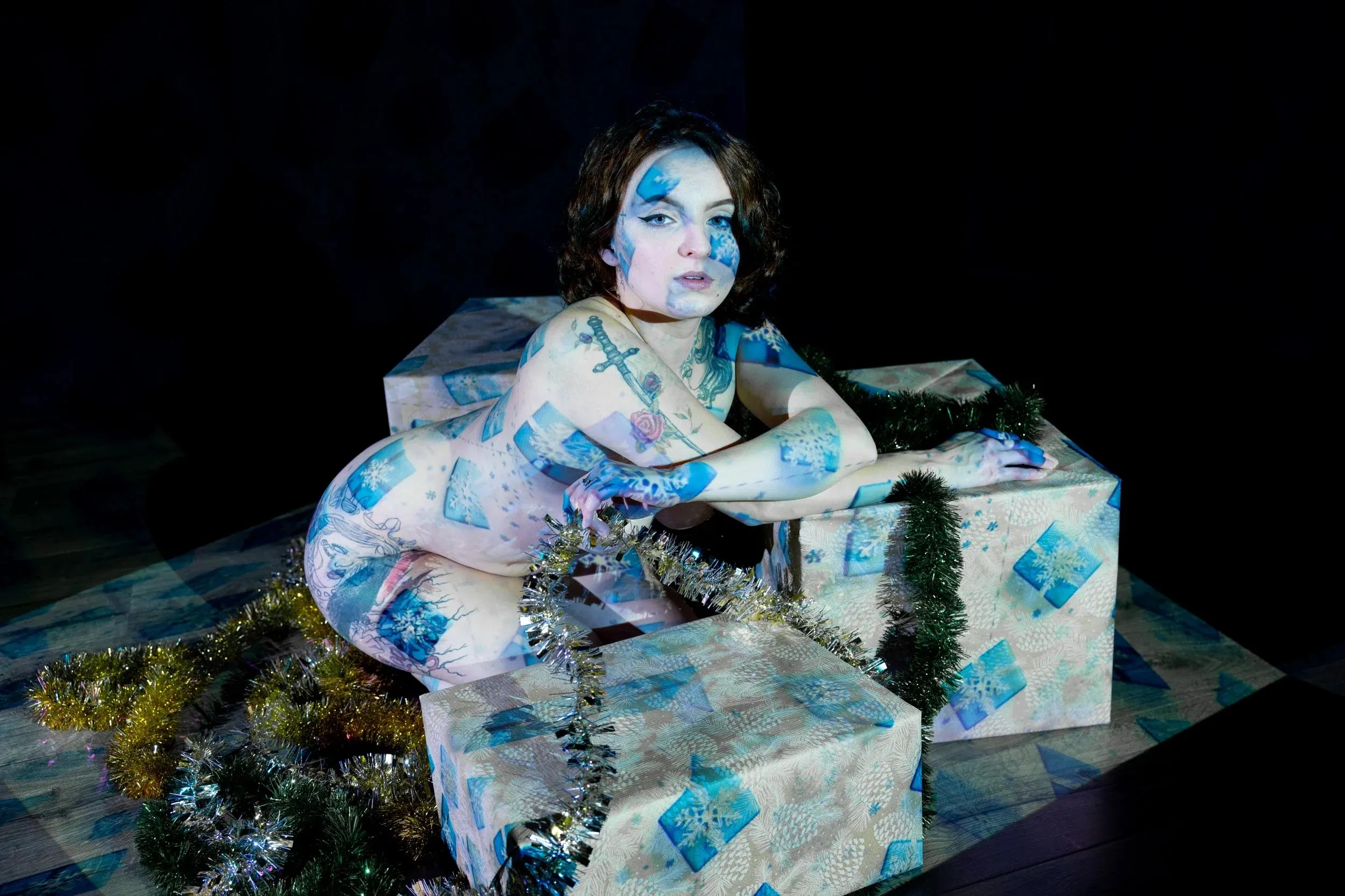 A woman leans across stacked boxes covered in pale blue projection.