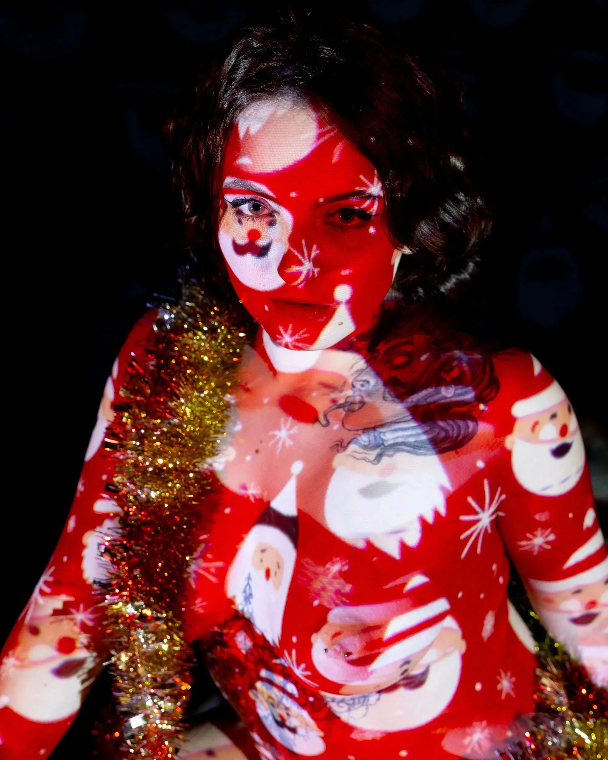 A woman looks toward the camera through red-and-white holiday projection.