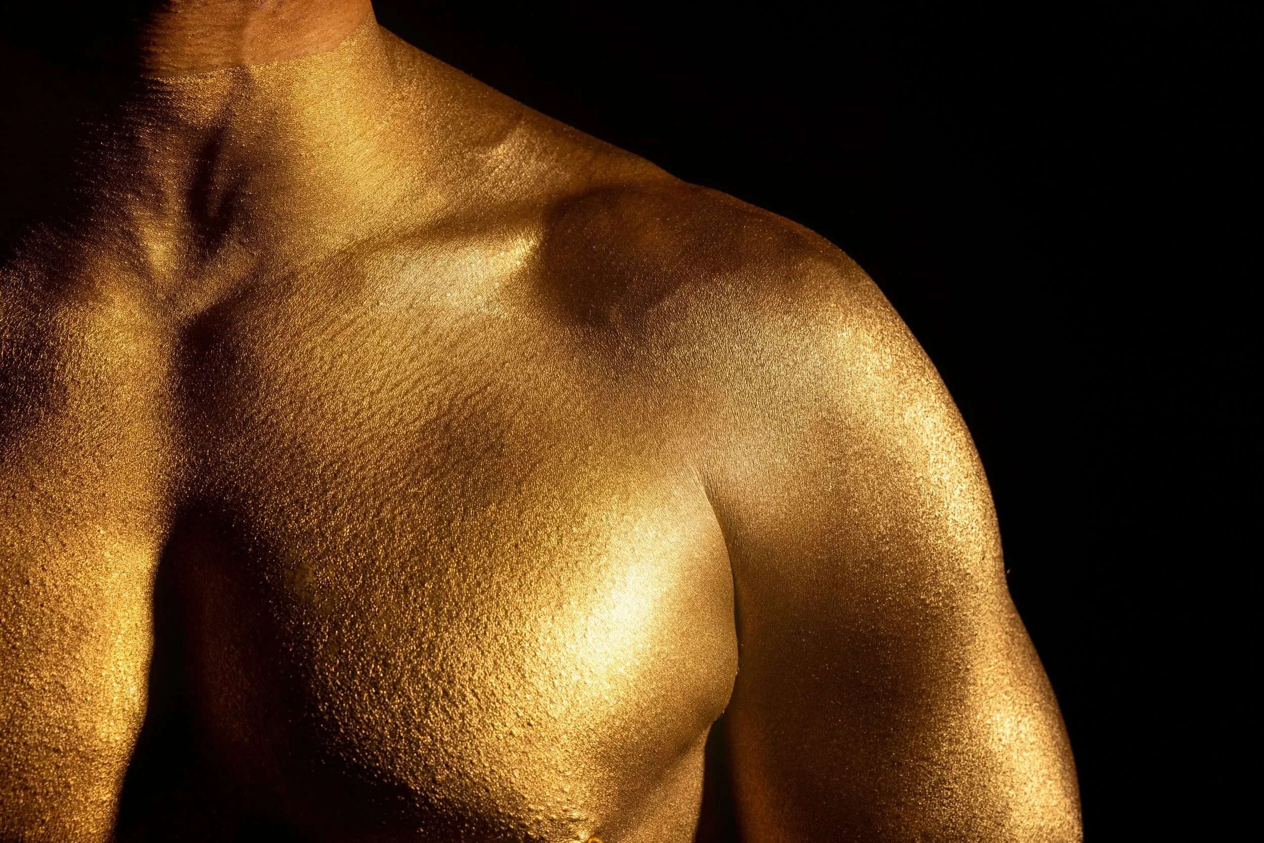 A shoulder and chest form bold gold shapes against black.