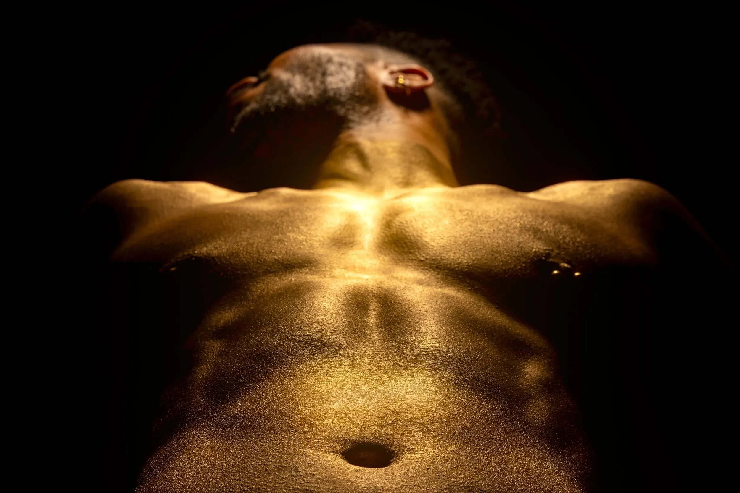 Warm light rakes across a gold-painted chest in a low-angle crop.