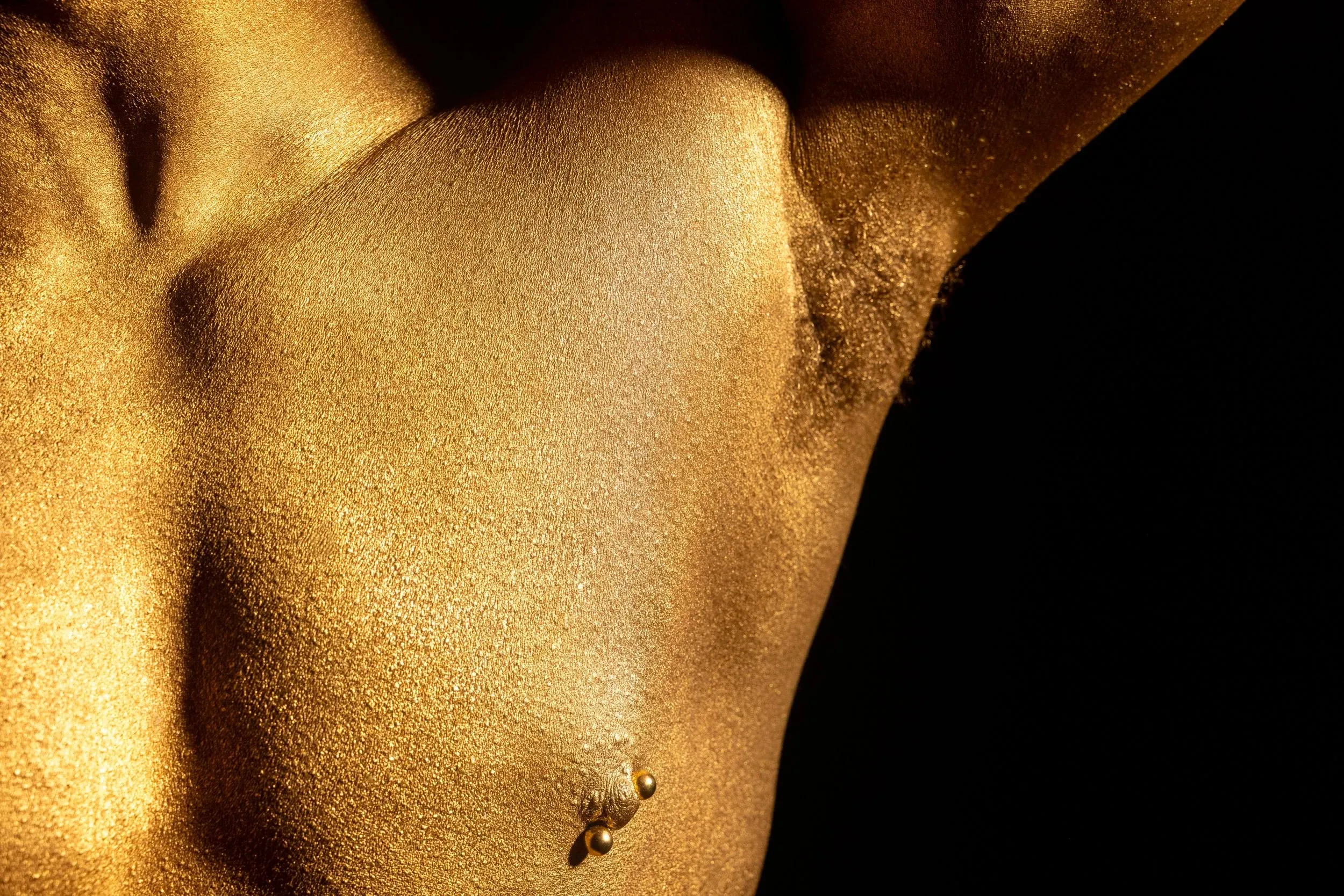 An extreme close-up shows gold-painted skin and a raised arm.
