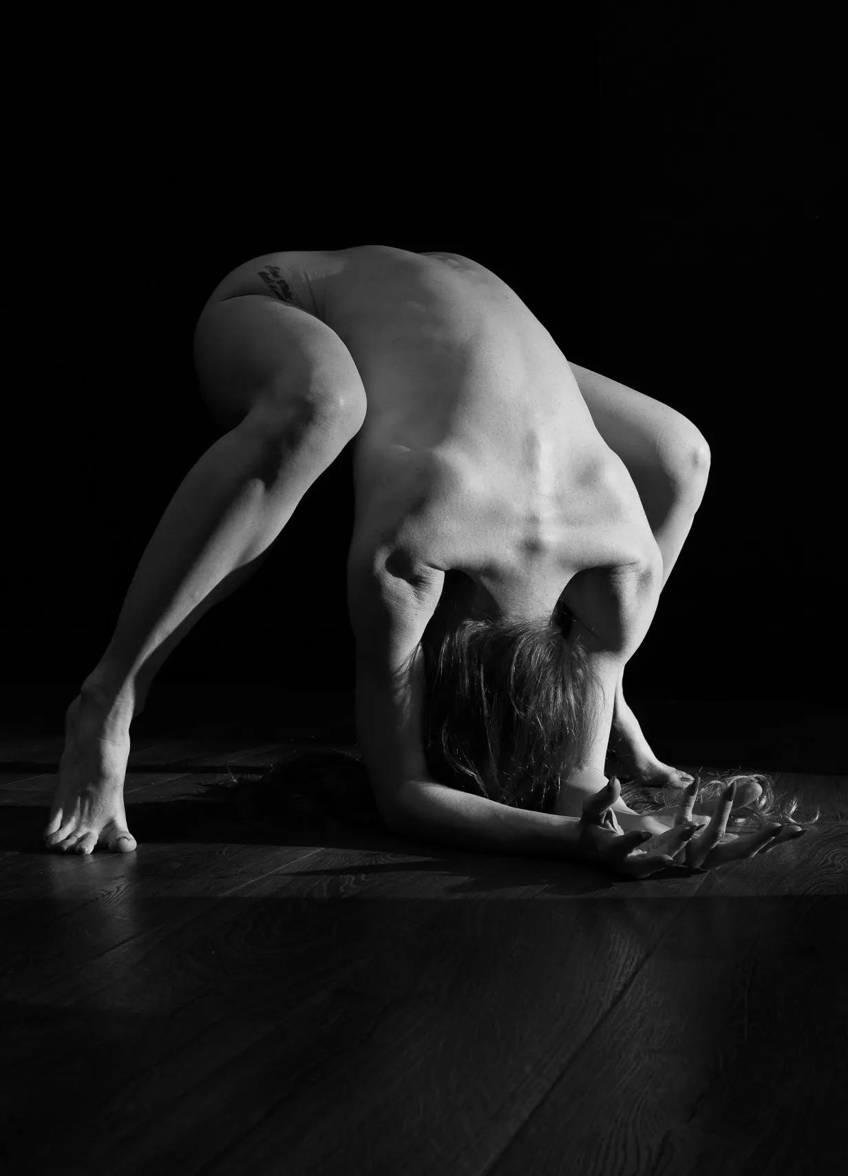 A woman strikes a unique pose, her upper body leans into the floor, her hands outstretched.