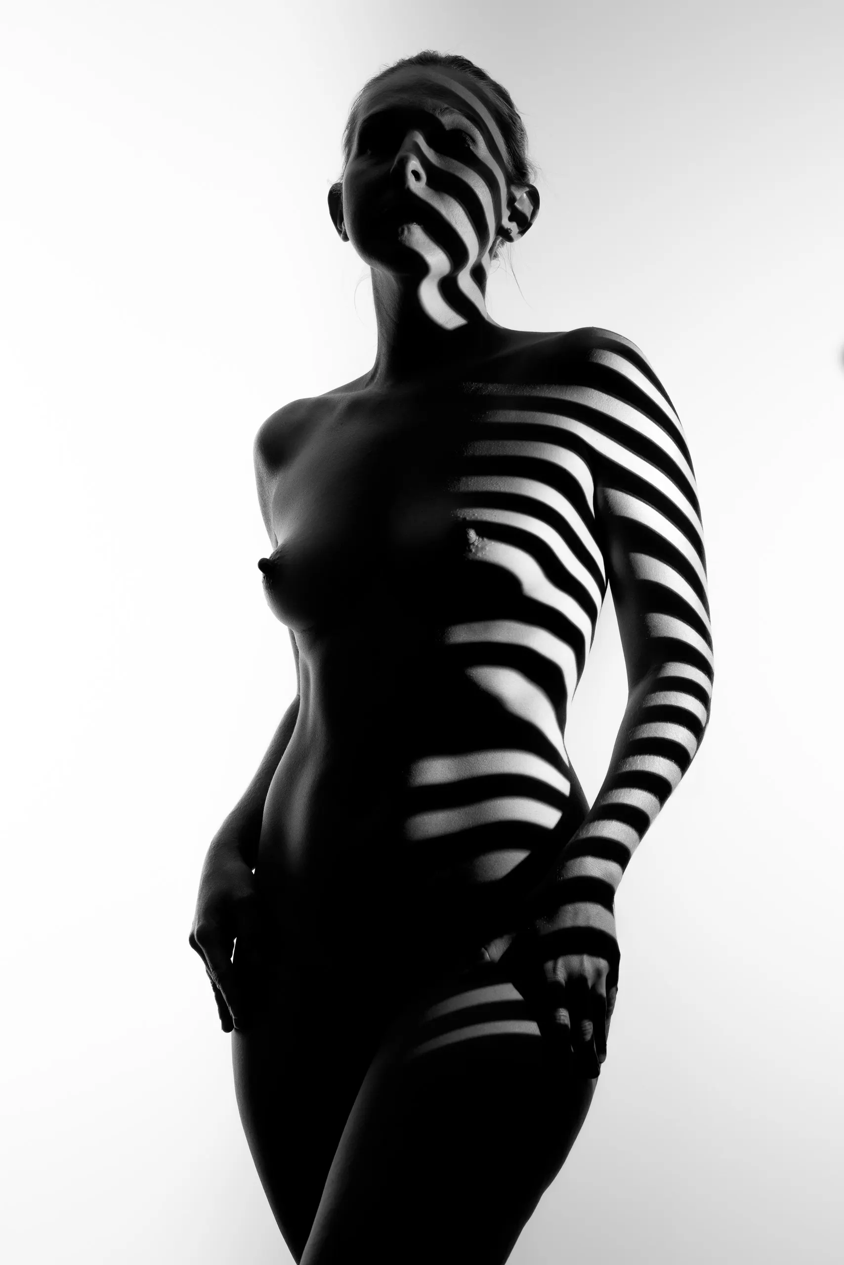 Projected black-and-white stripes wrap a standing woman against white.
