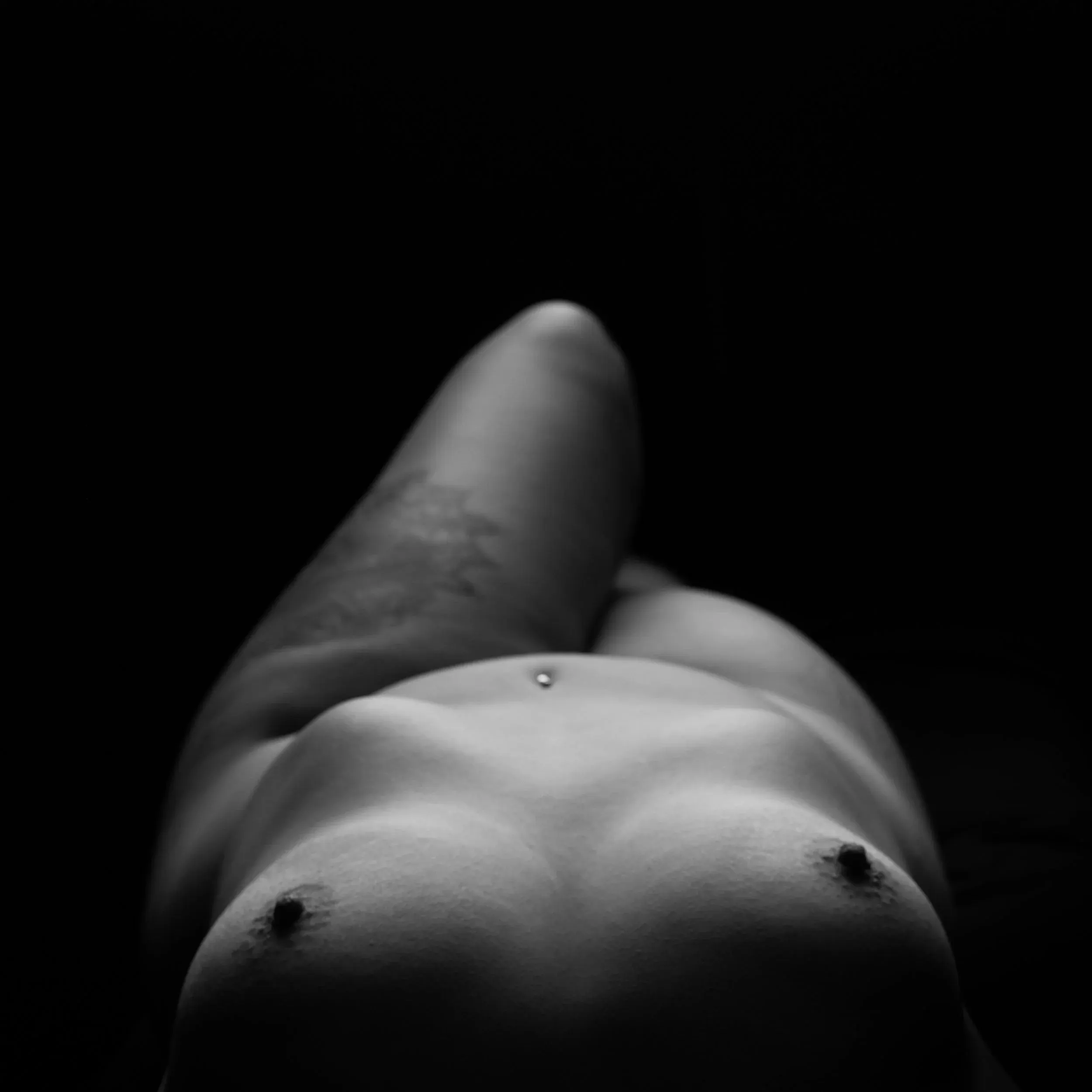 A low-angle portrait follows a reclining figure toward the dark background.