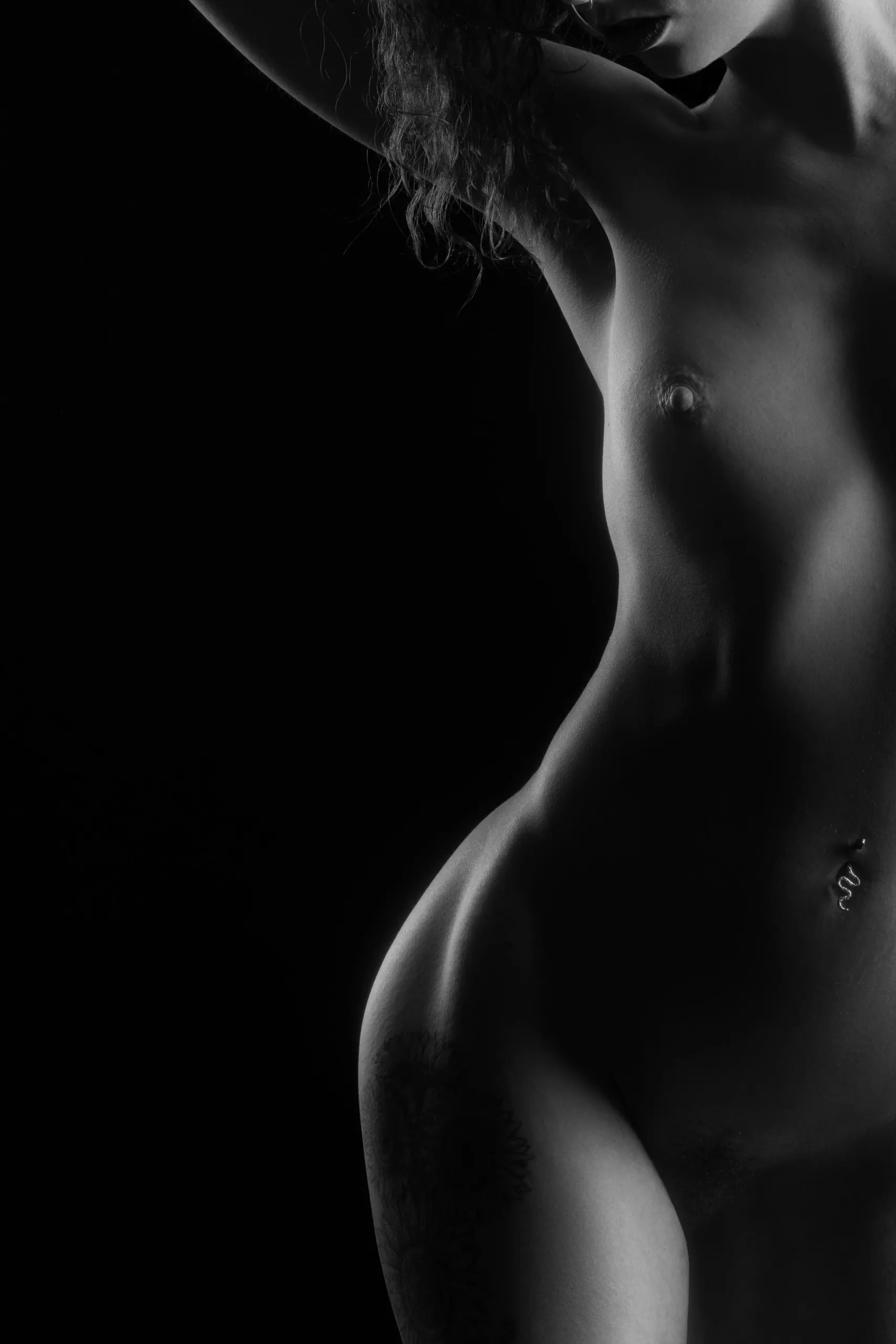 Hard side light outlines a standing figure against deep black.