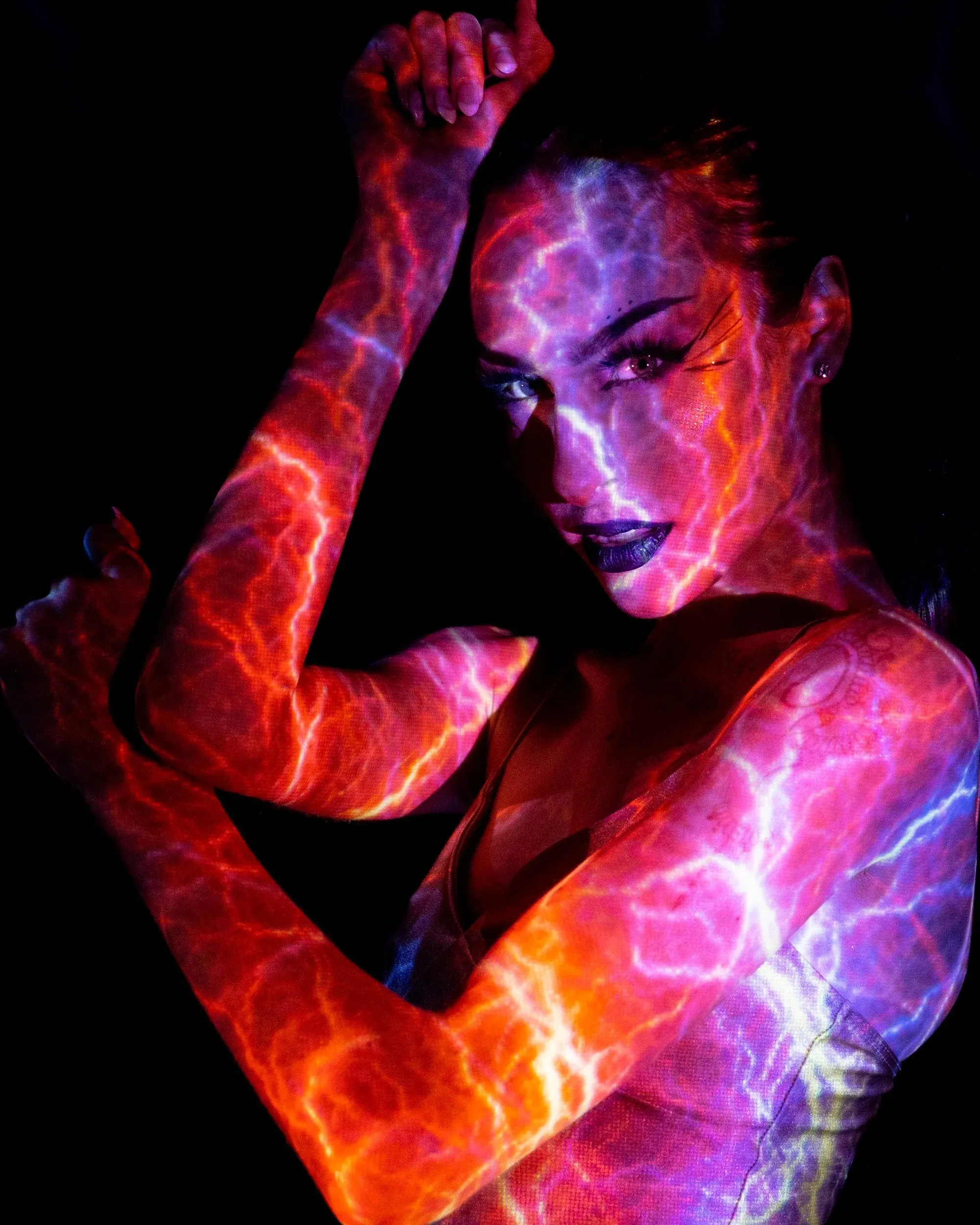 A close portrait overlays a woman with fiery red and violet textures projected onto her.