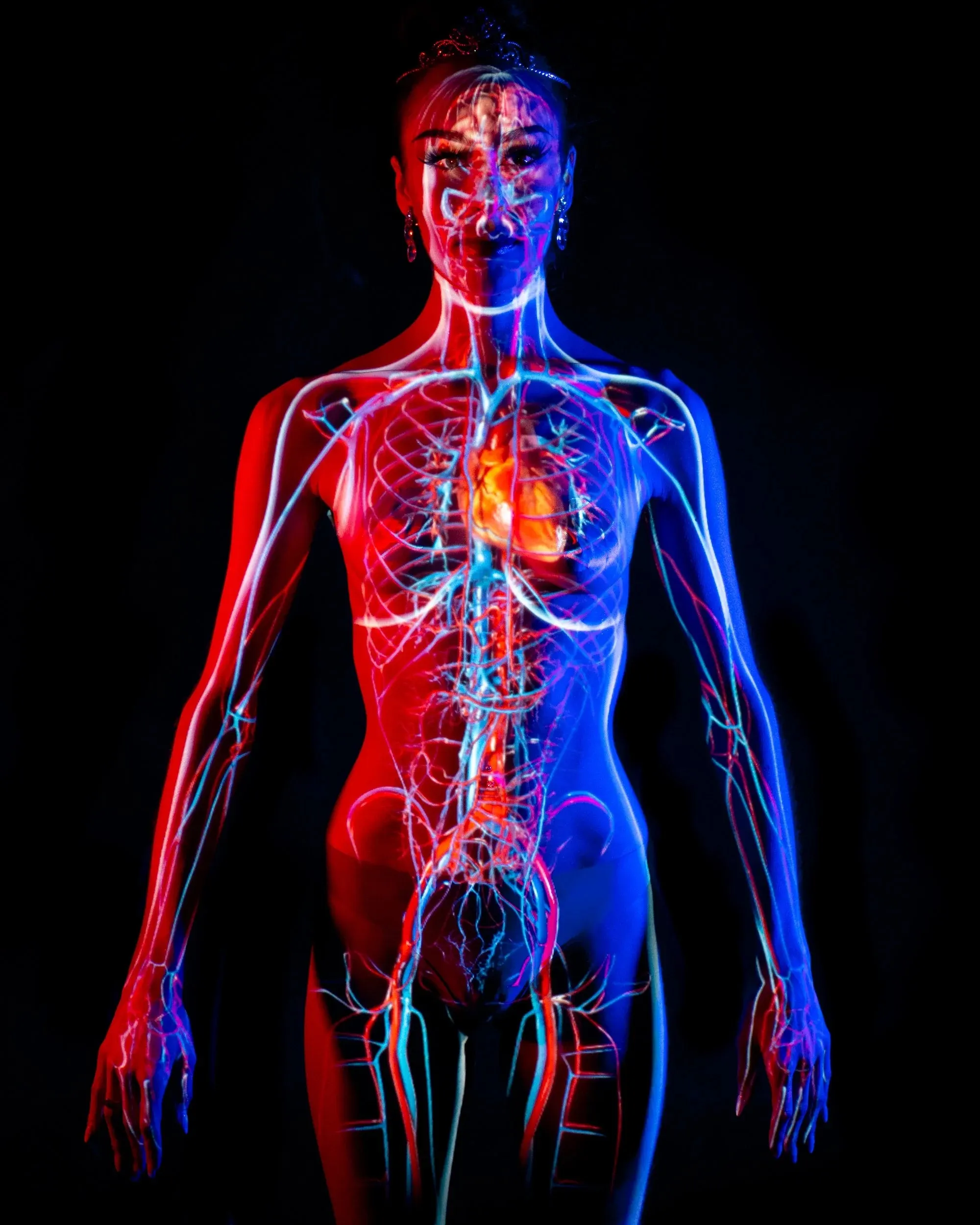 A luminous circulatory-system projection covers a standing woman against black.