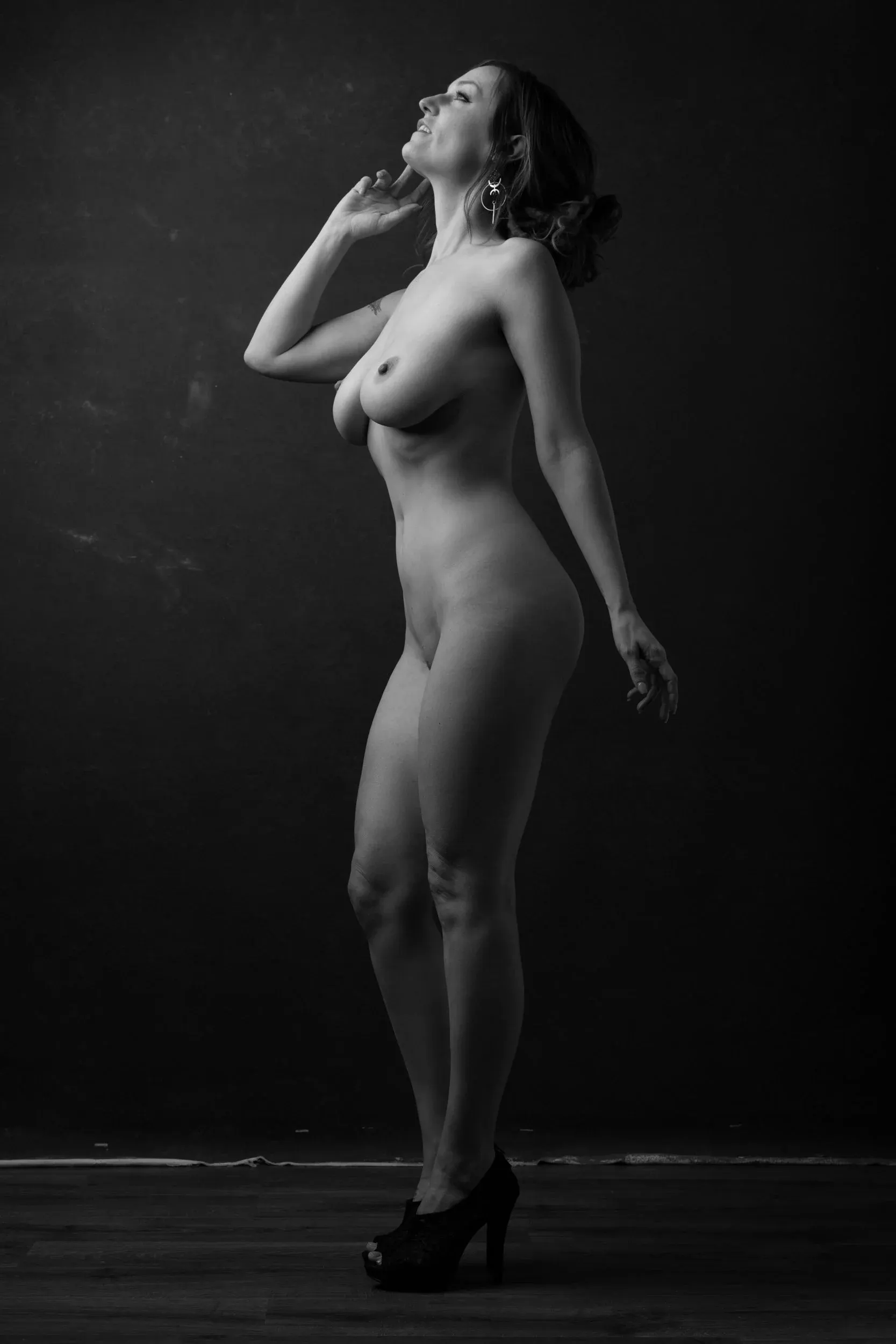 A standing woman leans back with her face lifted toward the light.