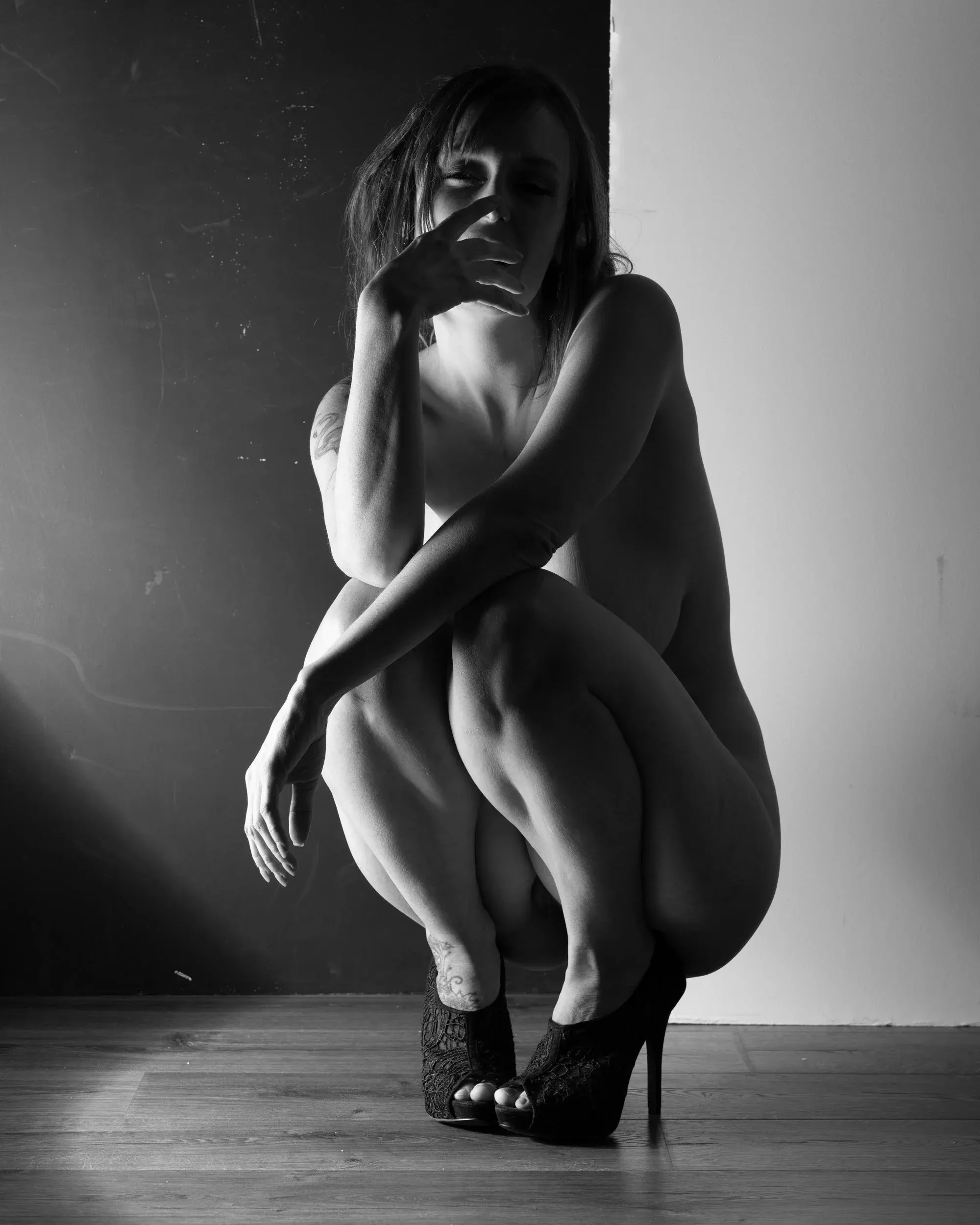 A woman folds one arm across her knees in a compact crouch.