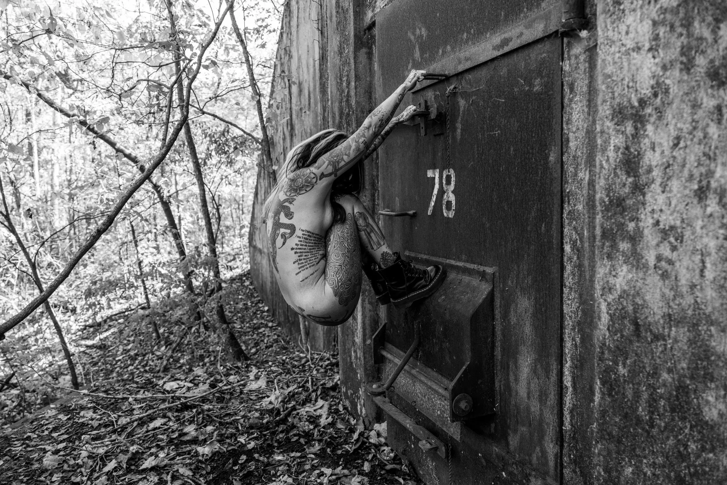 A woman clings diagonally to the bunker door marked 78.