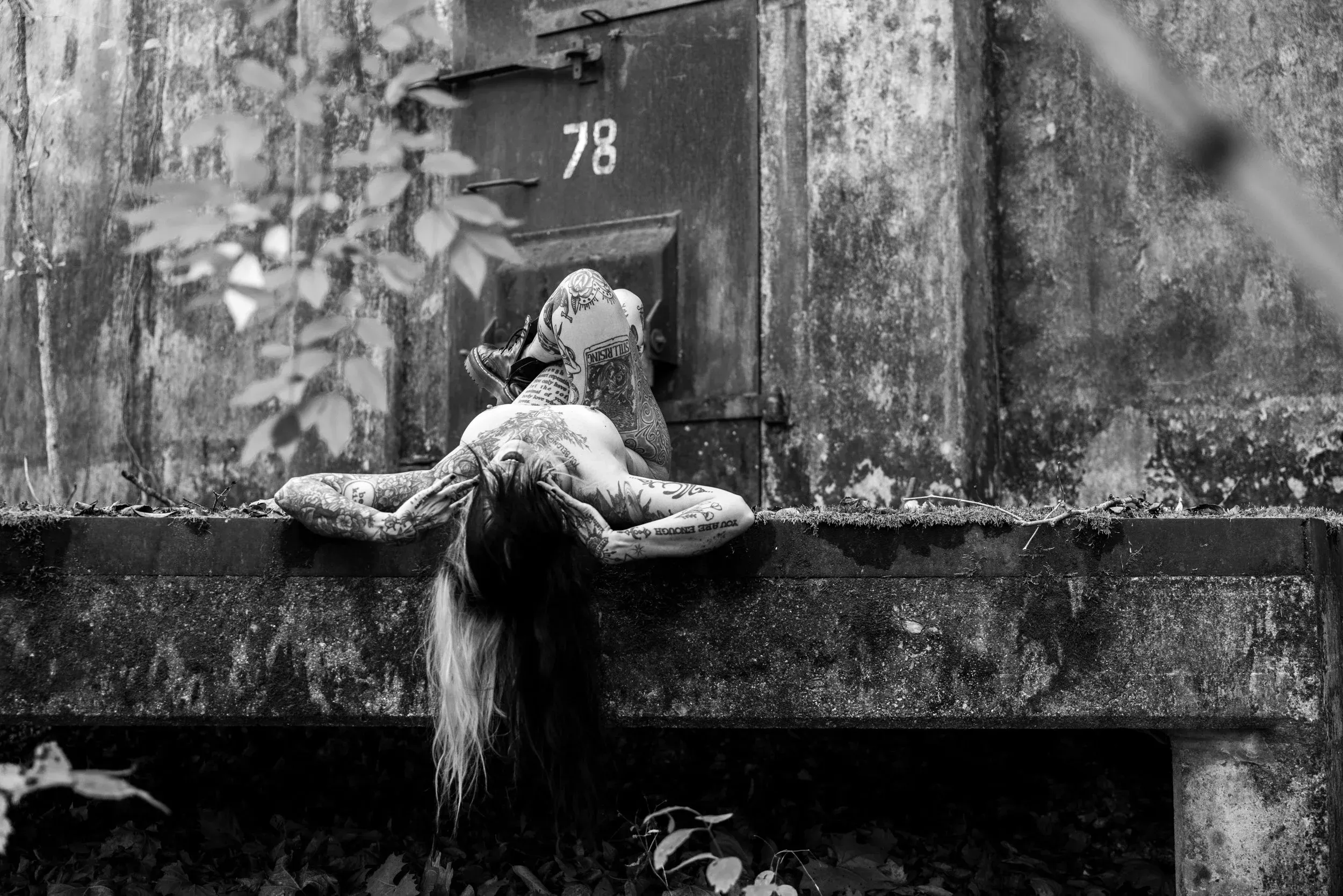 A woman reclines backward across a concrete ledge before Bunker 78.