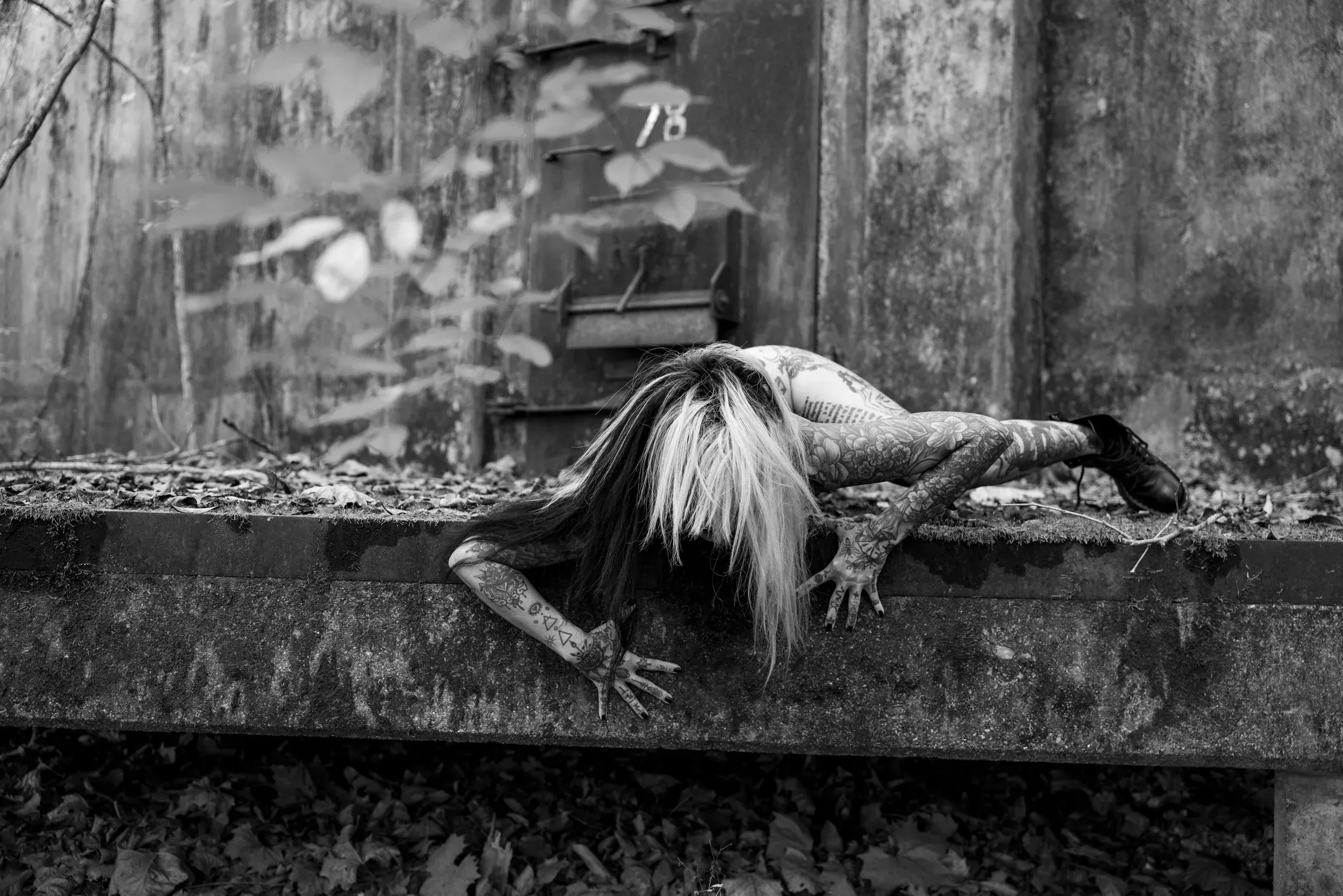 A woman stretches face-down across a mossy concrete ledge.