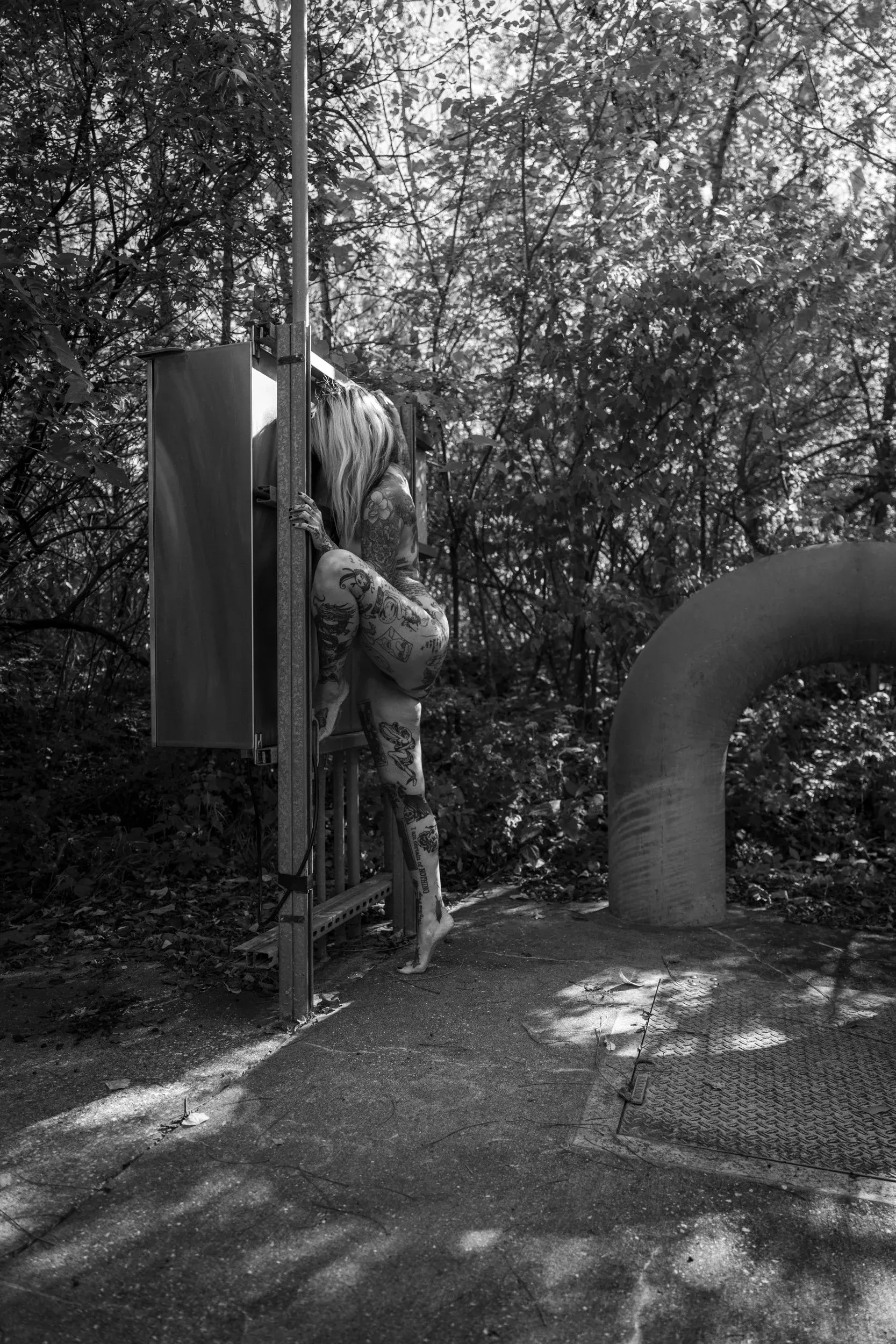 A woman climbs industrial equipment surrounded by dense woods.