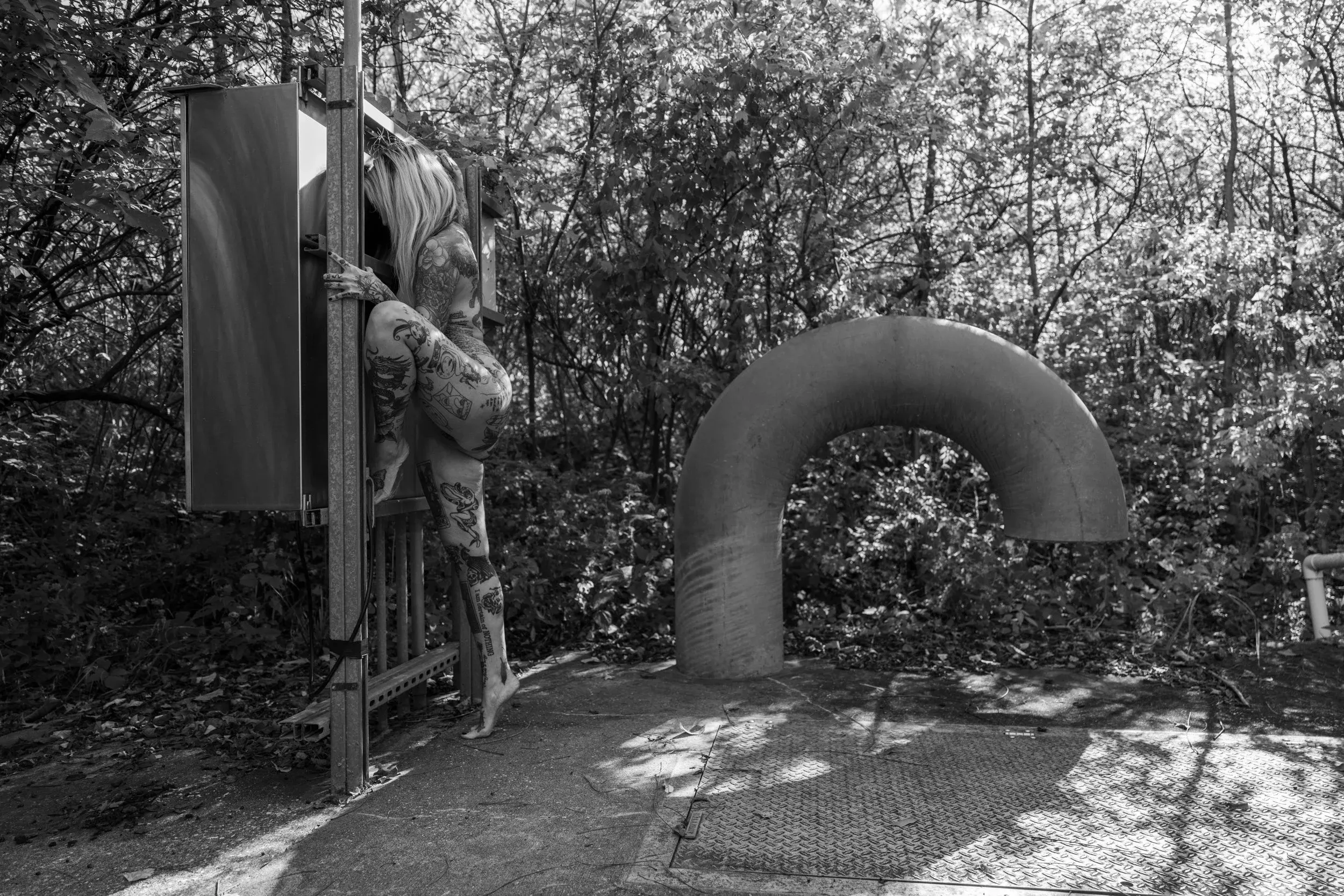A wide view places a small figure among curved pipes and forest shadows.