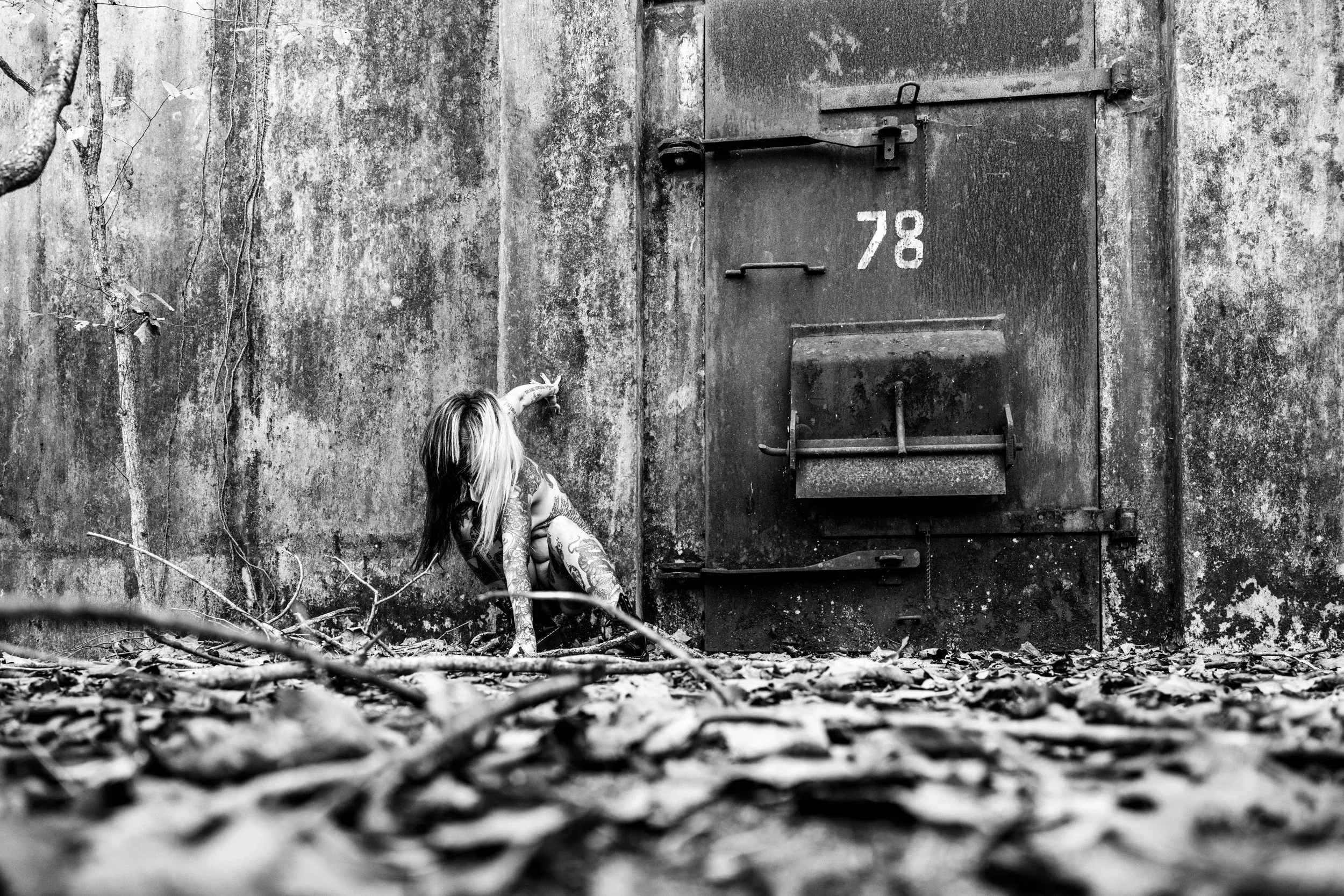 A woman crouches before the weathered door marked 78.