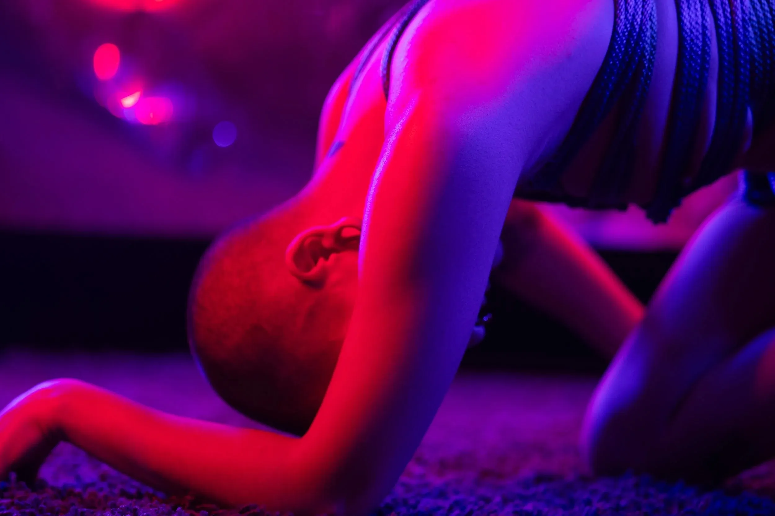 A close view captures a person bending forward under saturated red light.