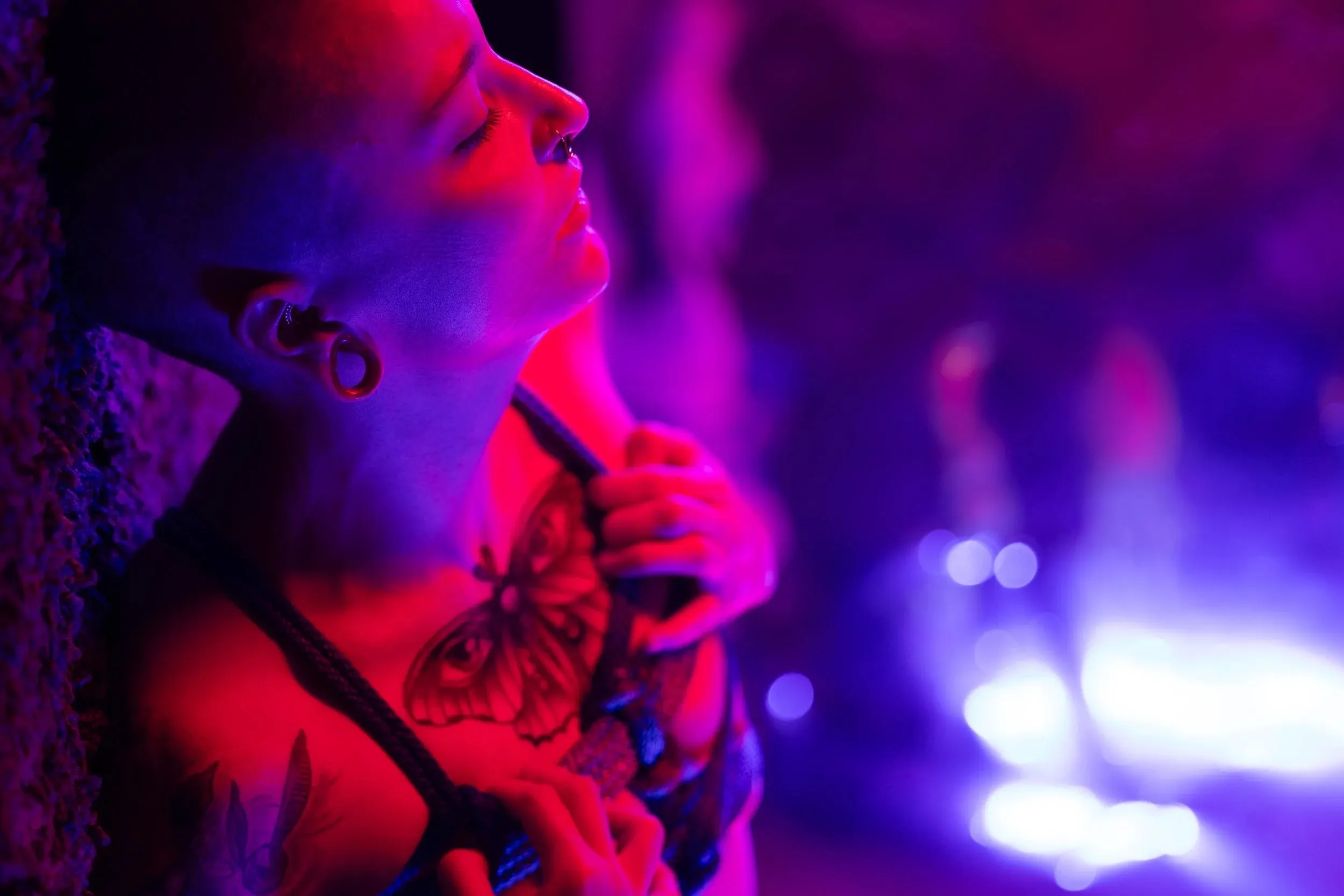 A close profile studies a bowed head and rope in purple haze.