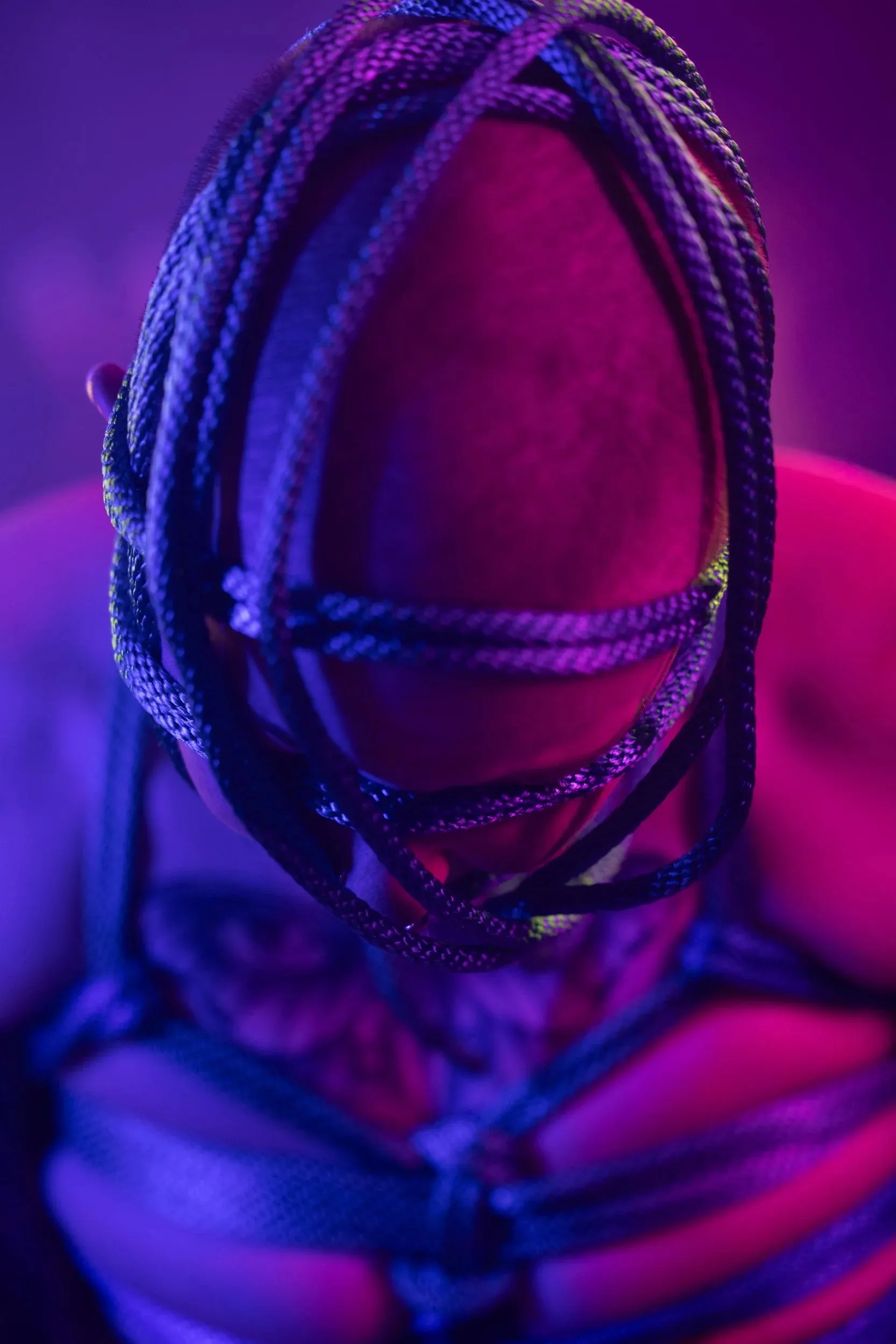 A close portrait shows an intricate rope hood glowing blue and magenta.