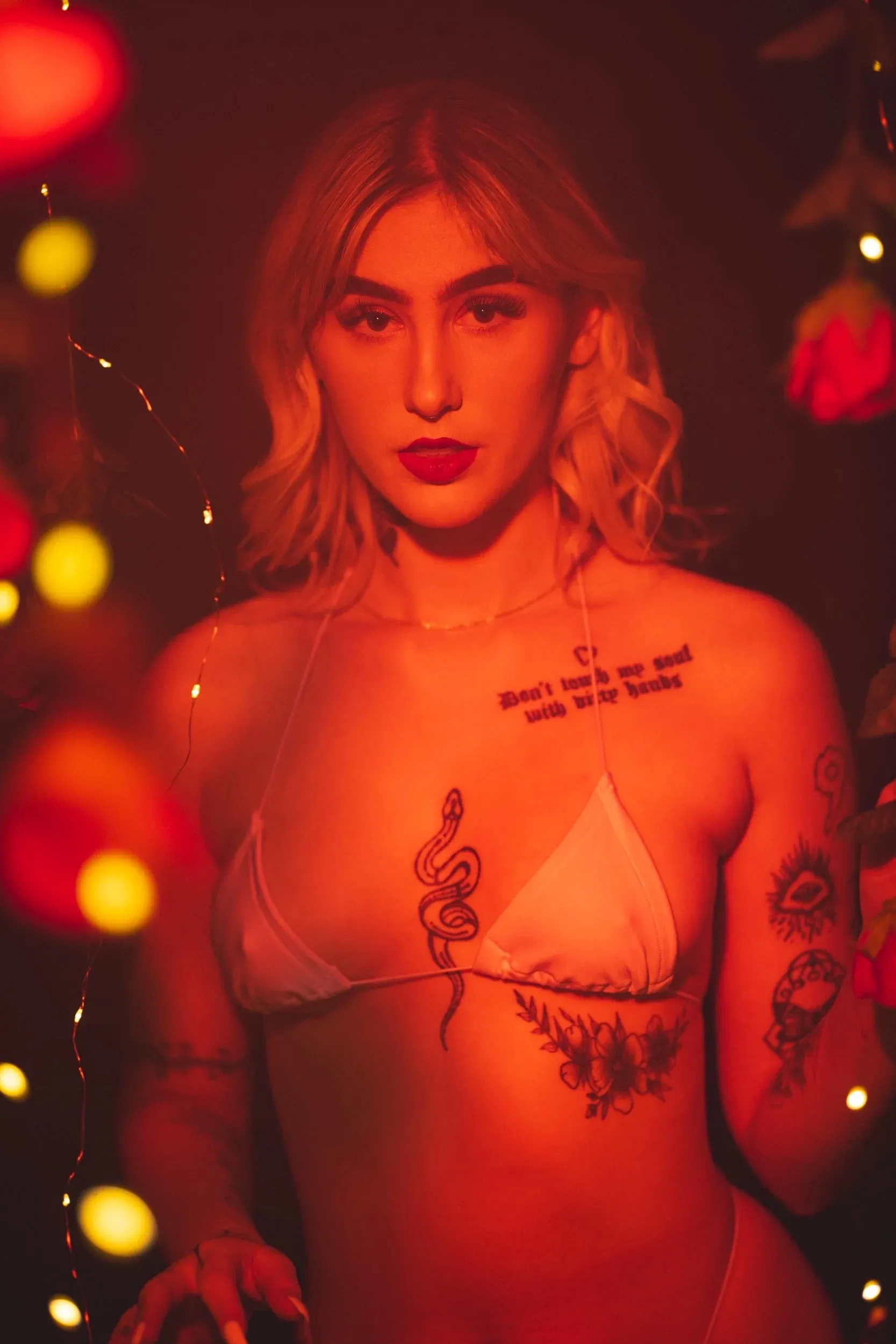 A woman faces forward as dense red and gold bokeh fills the frame.