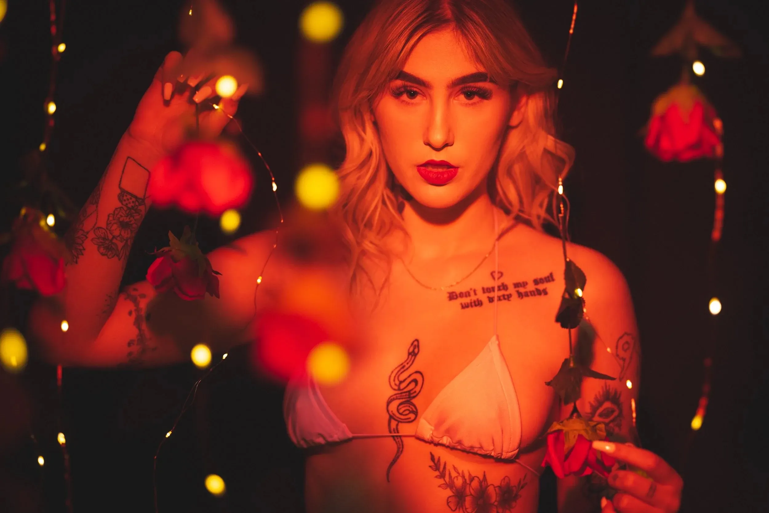 A direct portrait frames a woman between red roses and golden bokeh.