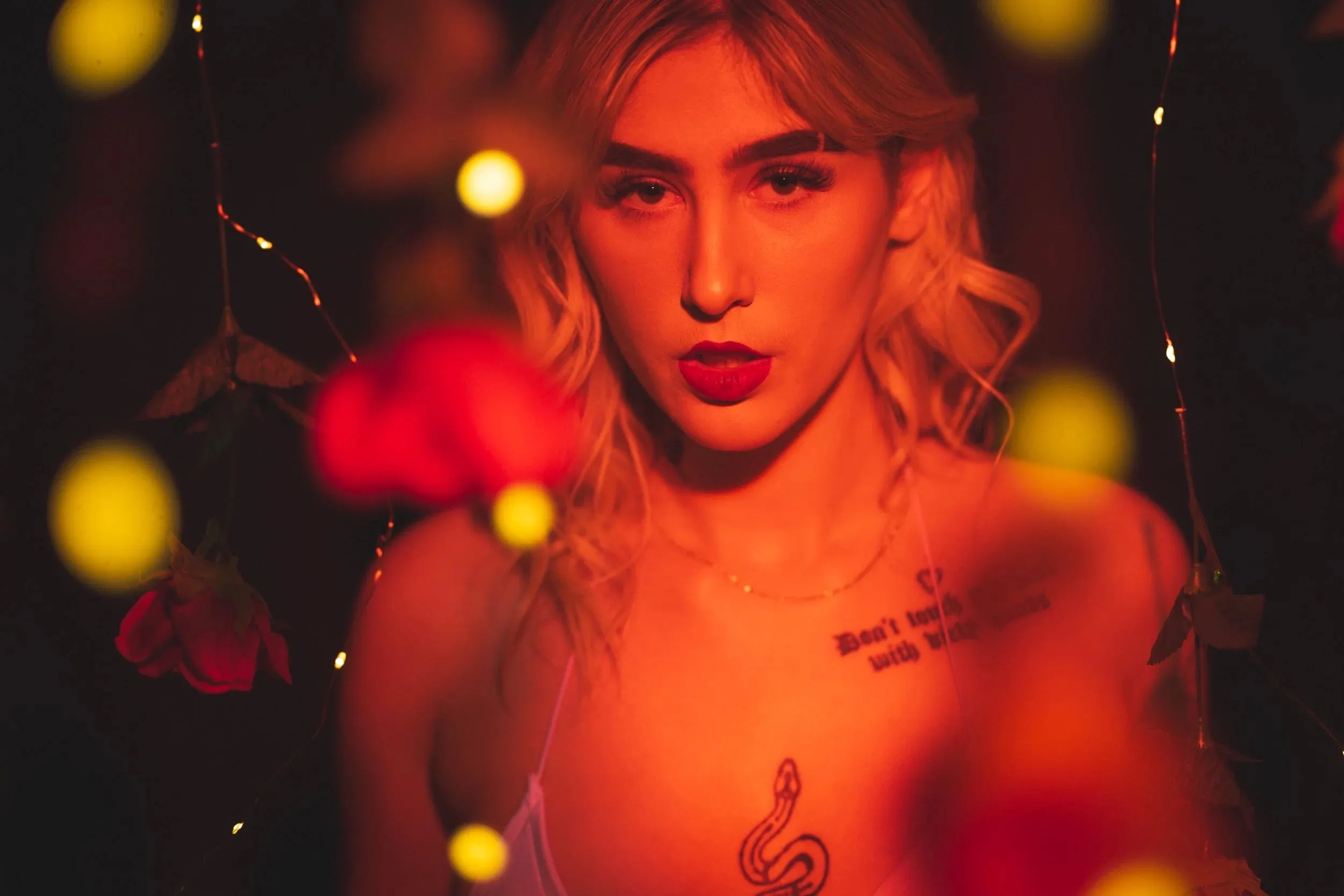 A woman purses her lips toward the camera through golden bokeh.