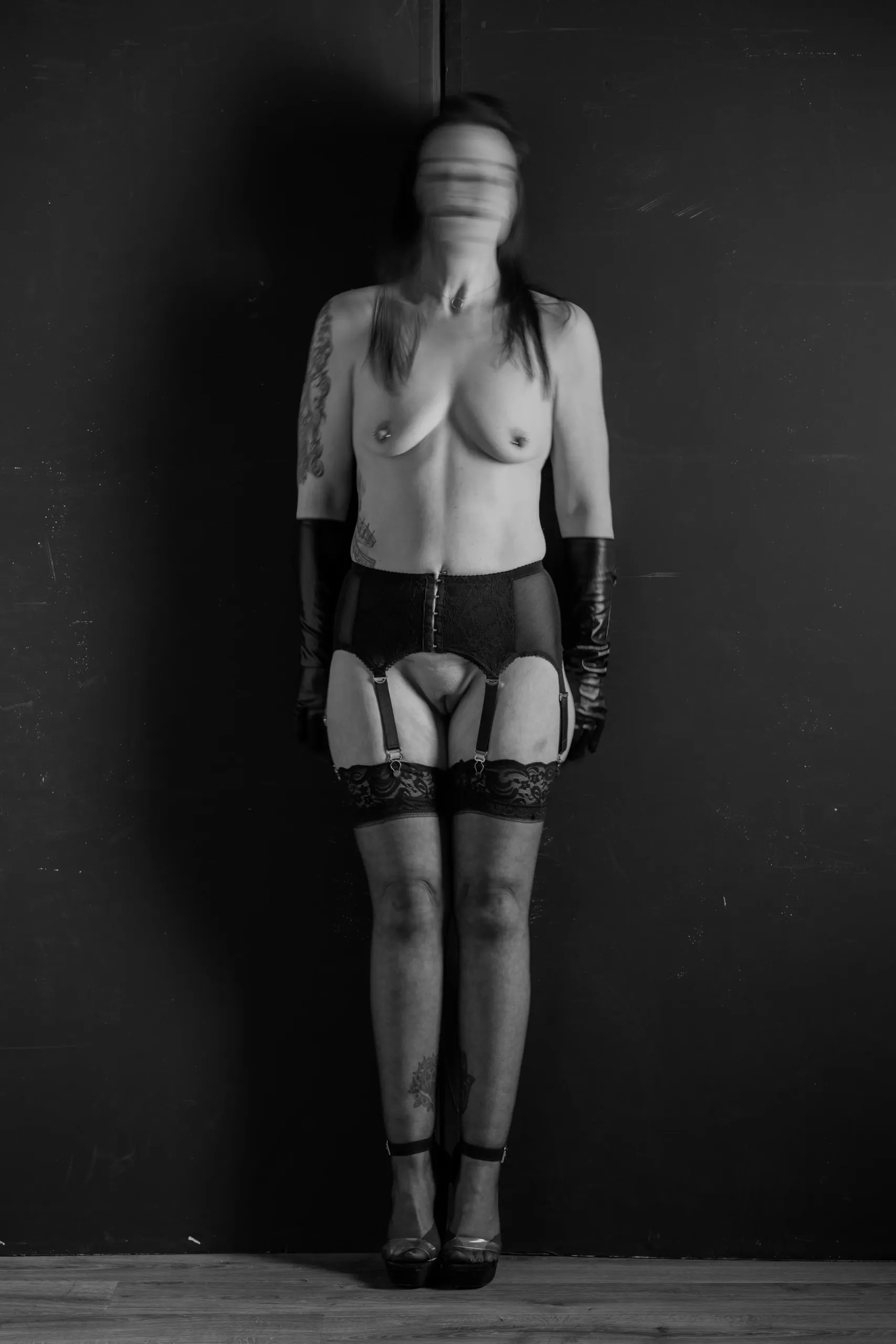 A standing figure in lingerie and gloves blurs into a ghostlike vertical portrait.